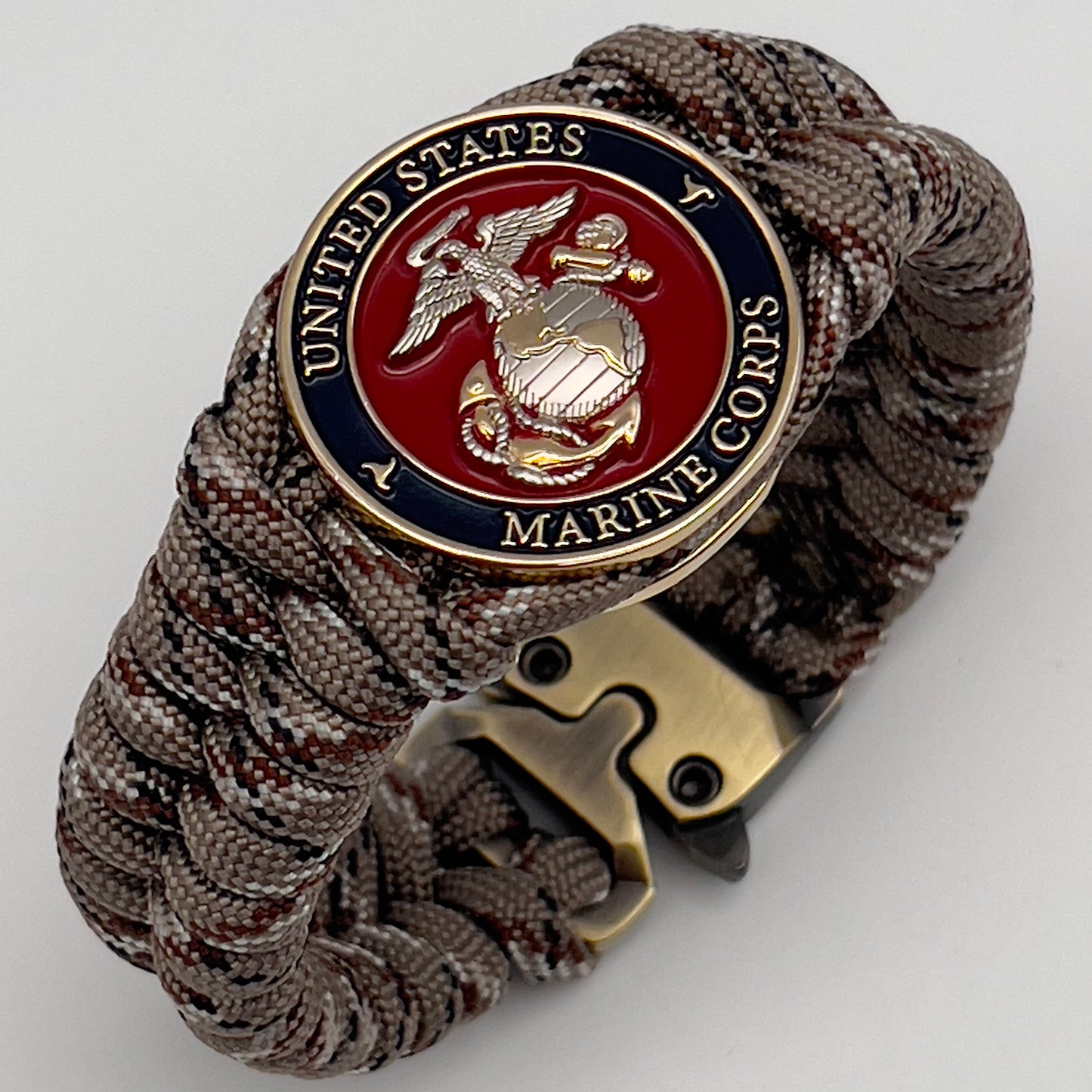 Thick and comfortable braided United States Marine Corps bracelet featuring a 24K gold and silver plated USMC officer Eagle Globe and Anchor medallion, a Cobra style tactical buckle and woven with Desert Camo paracord.