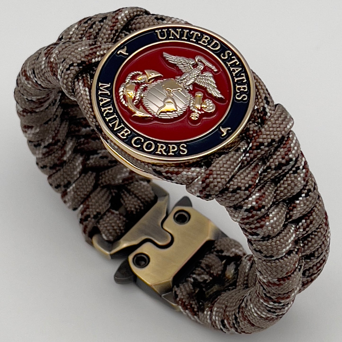 Thick and comfortable braided United States Marine Corps bracelet featuring a 24K gold and silver plated USMC officer Eagle Globe and Anchor medallion, a Cobra style tactical buckle and woven with Desert Camo paracord.