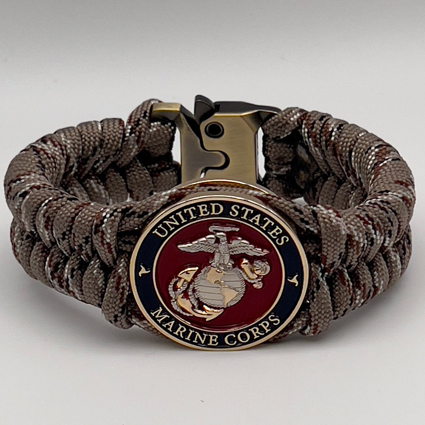 Thick and comfortable braided United States Marine Corps bracelet featuring a 24K gold and silver plated USMC officer Eagle Globe and Anchor medallion, a Cobra style tactical buckle and woven with Desert Camo paracord.