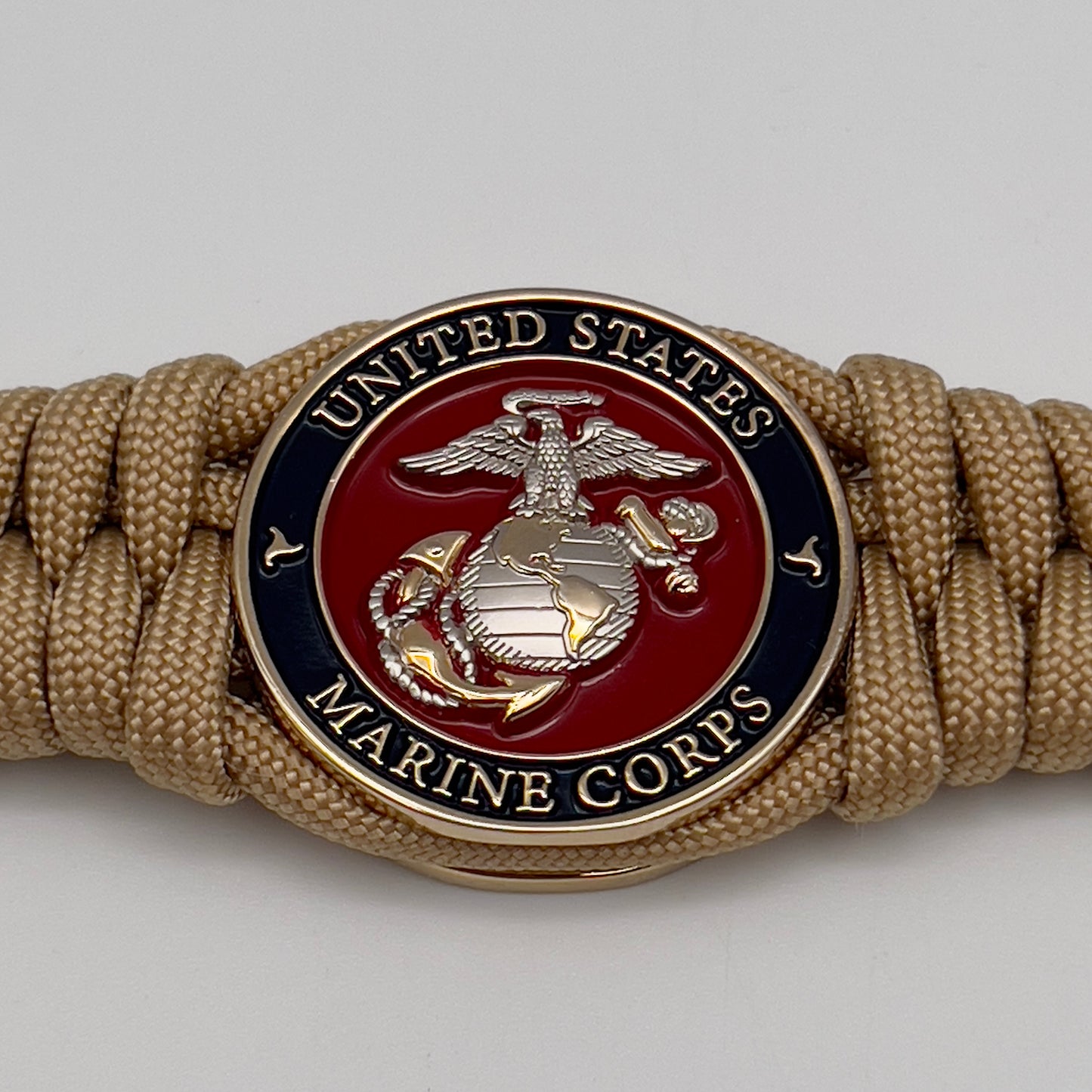 Thick and comfortable braided United States Marine Corps bracelet featuring a 24K gold and silver plated USMC officer Eagle Globe and Anchor medallion, a Cobra style tactical buckle and woven with gold 550 paracord.