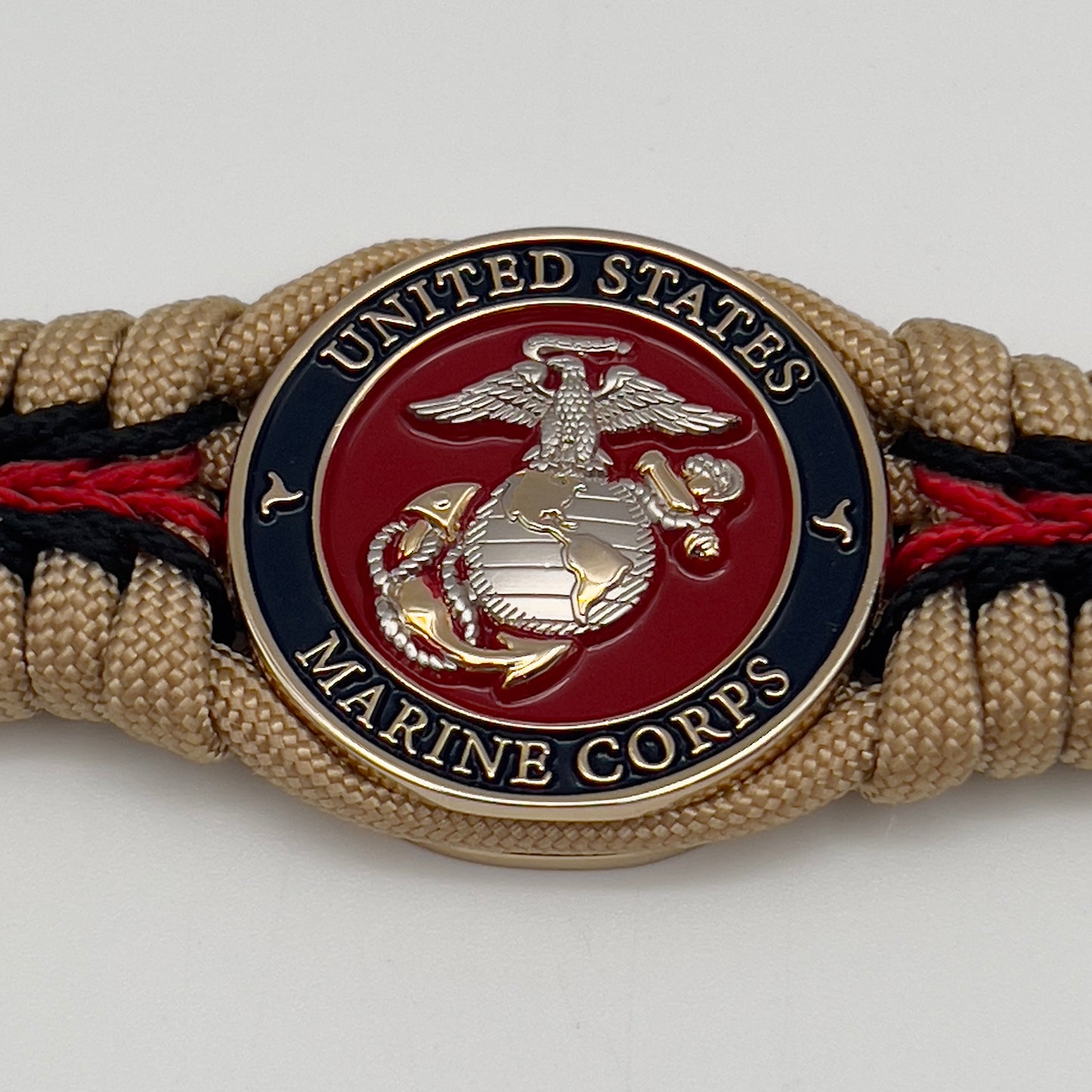 Thick and comfortable braided United States Marine Corps bracelet featuring a 24K gold and silver plated USMC officer Eagle Globe and Anchor medallion, a Cobra style tactical buckle and woven with gold 550 and Imperial red micro paracord.