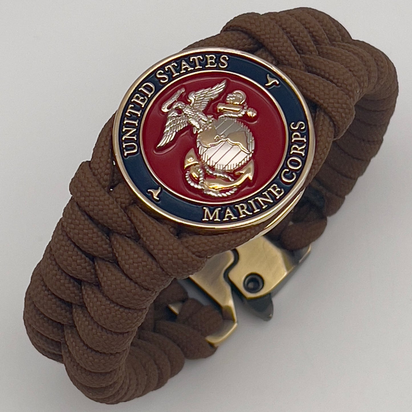 Thick and comfortable braided United States Marine Corps bracelet featuring a 24K gold and silver plated USMC officer Eagle Globe and Anchor medallion, a Cobra style tactical buckle and woven with Coyote brown 550 paracord.