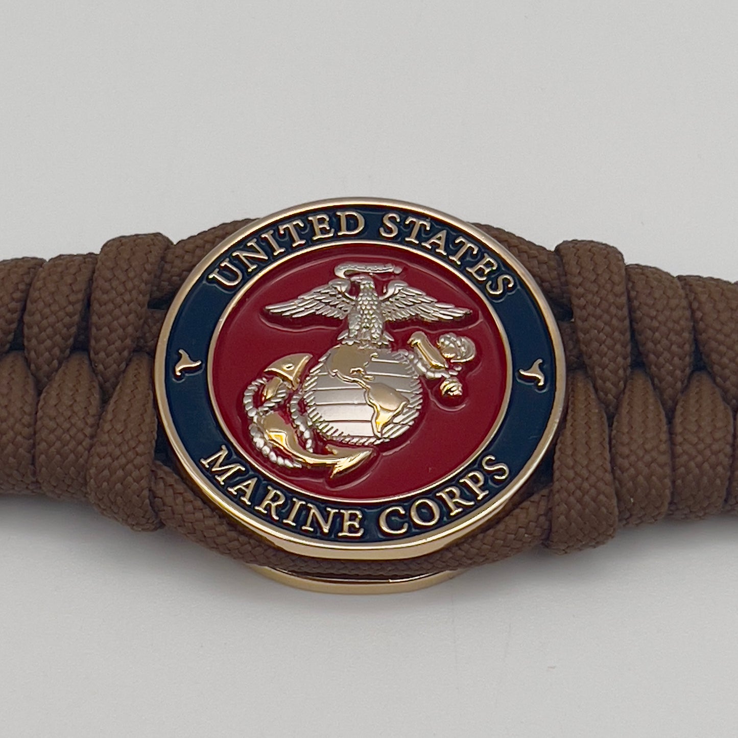 Thick and comfortable braided United States Marine Corps bracelet featuring a 24K gold and silver plated USMC officer Eagle Globe and Anchor medallion, a Cobra style tactical buckle and woven with Coyote brown 550 paracord.