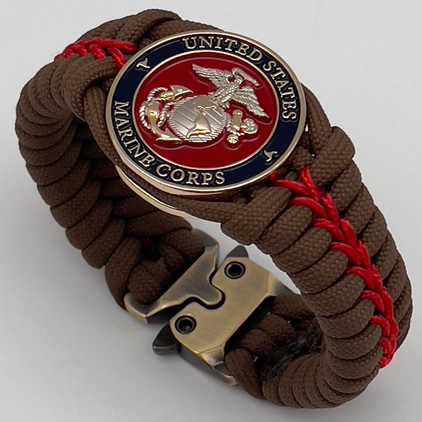 Thick, semi-rigid and comfortable braided United States Marine Corps bracelet featuring a 24K gold and silver plated USMC officer Eagle Globe and Anchor medallion, a Cobra style tactical buckle and woven with Coyote brown 550 and Imperial red micro paracord.