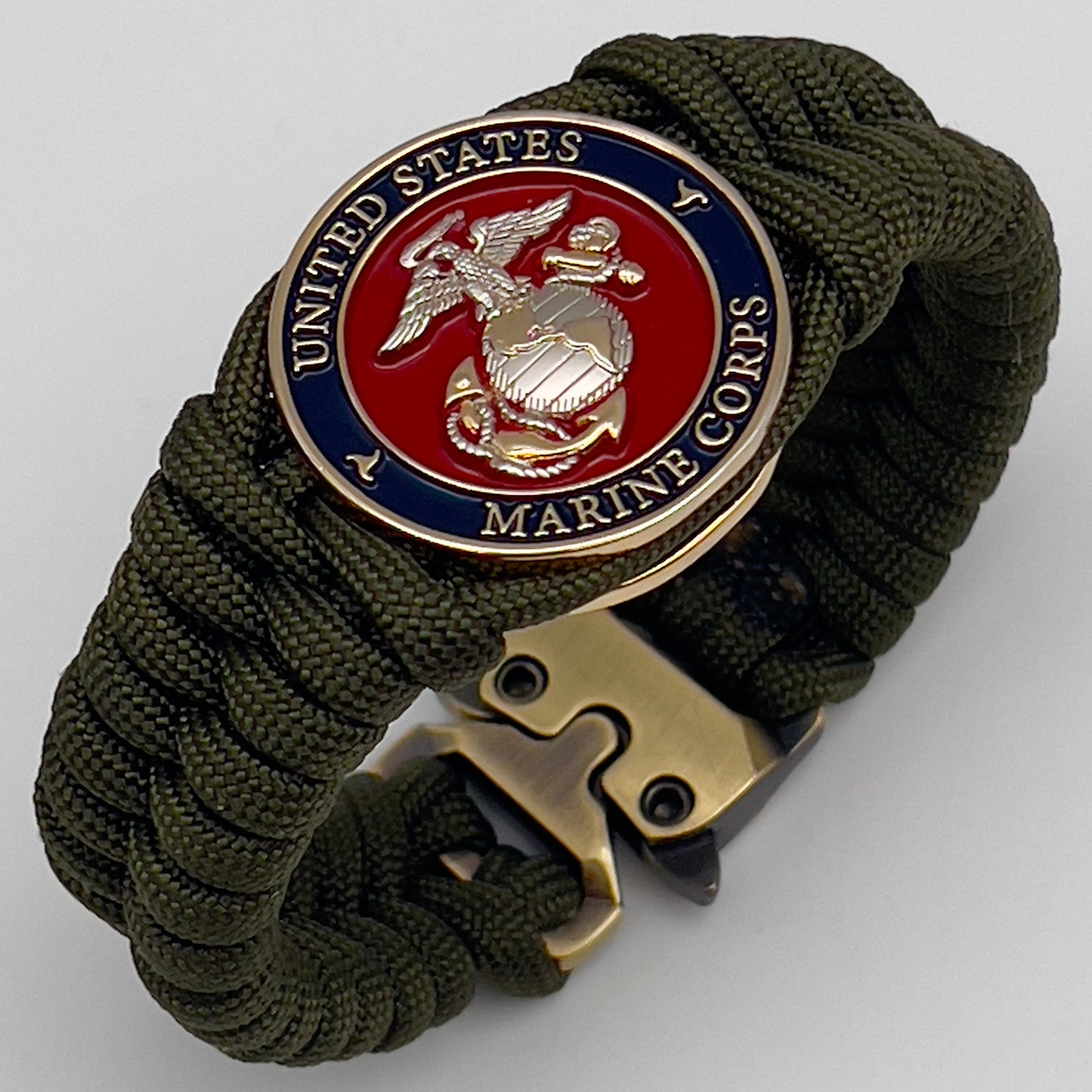 Thick, semi-rigid and comfortable braided United States Marine Corps bracelet featuring a 24K gold and silver plated USMC officer Eagle Globe and Anchor medallion, a gold Cobra style tactical buckle and woven with olive drab 550 paracord.