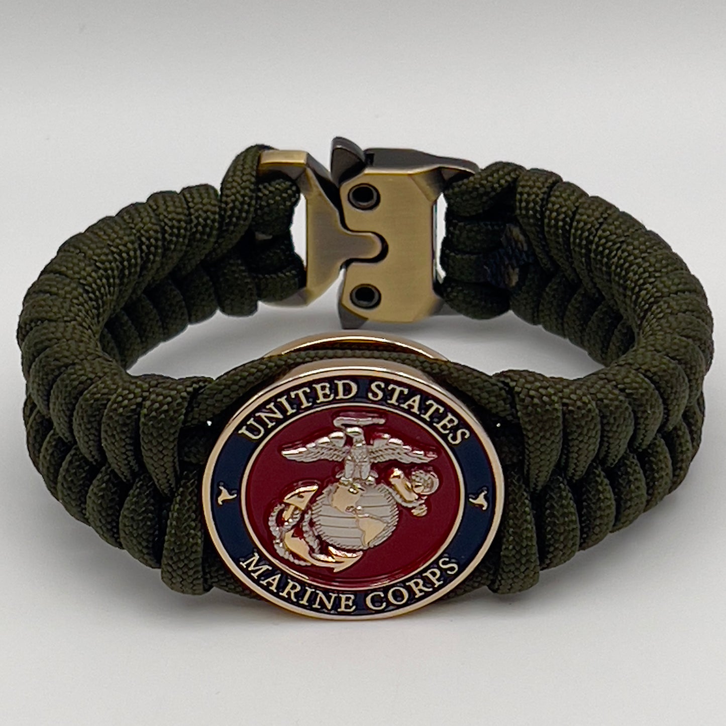 Thick, semi-rigid and comfortable braided United States Marine Corps bracelet featuring a 24K gold and silver plated USMC officer Eagle Globe and Anchor medallion, a gold Cobra style tactical buckle and woven with olive drab 550 paracord.