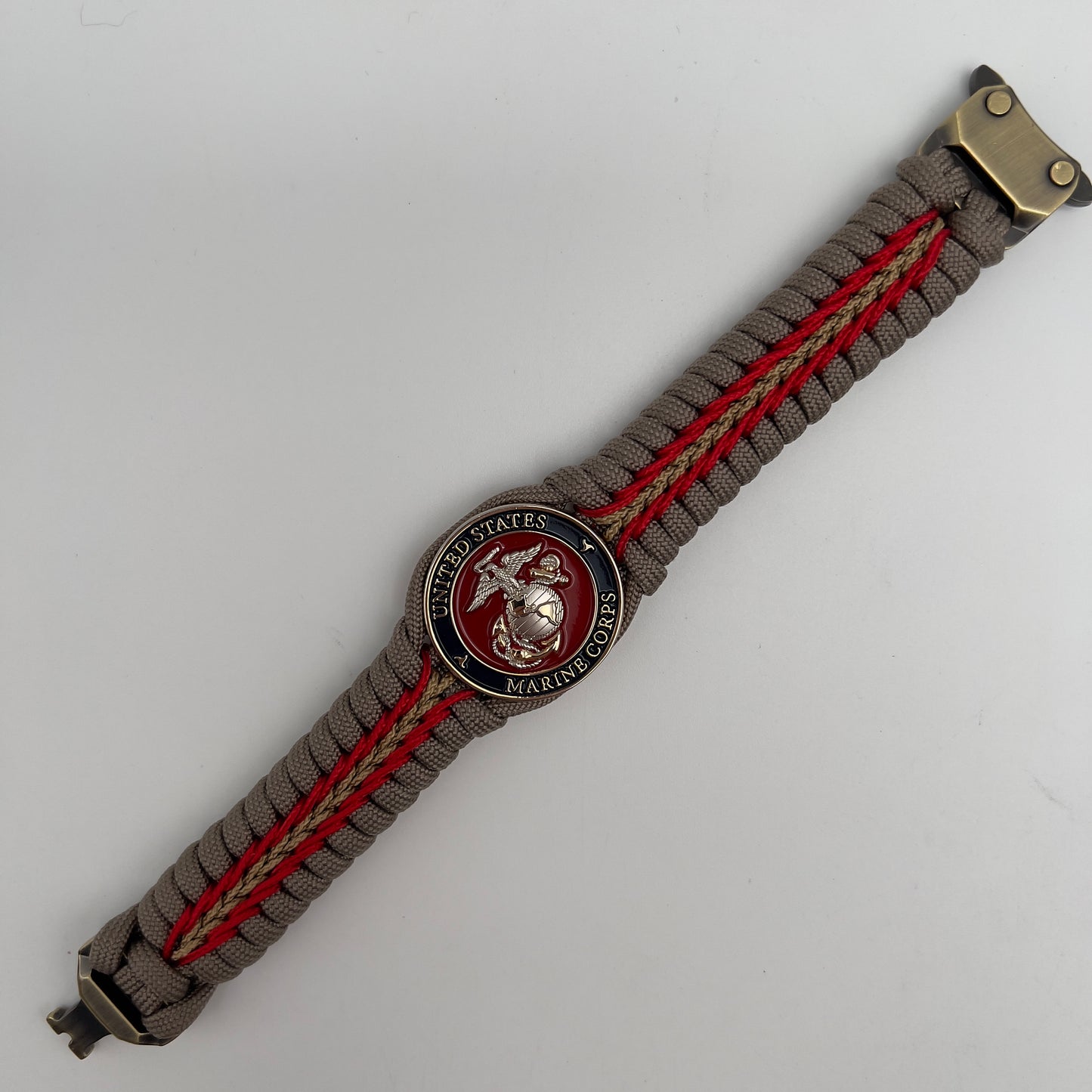 Thick and comfortable braided United States Marine Corps bracelet featuring a 24K gold and silver plated USMC officer Eagle Globe and Anchor medallion, a Cobra style tactical buckle and woven with tan 550, Imperial red and gold micro paracord.