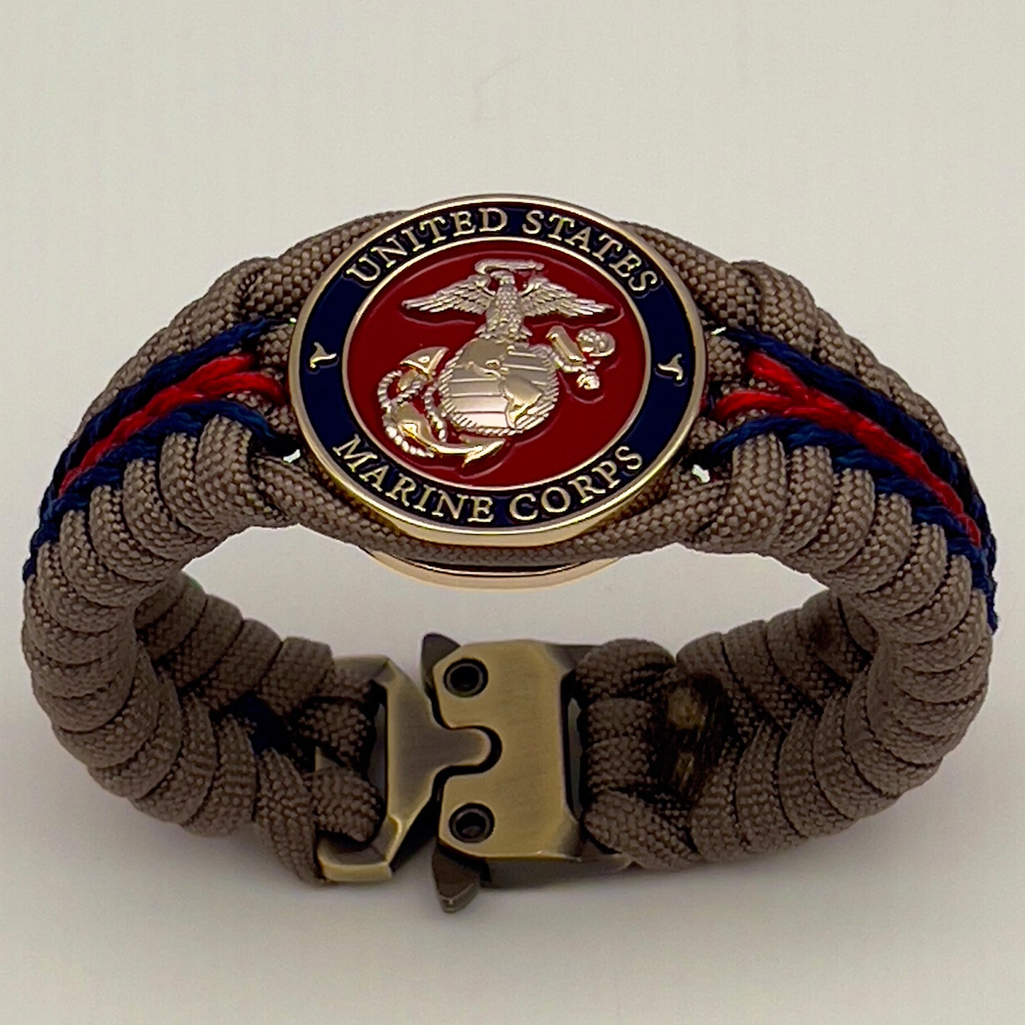 Thick, semi-rigid and comfortable braided United States Marine Corps bracelet featuring a 24K gold and silver plated USMC officer Eagle Globe and Anchor medallion, a gold Cobra style tactical buckle and woven with tan 550 paracord and Imperial red and gold micro cord.