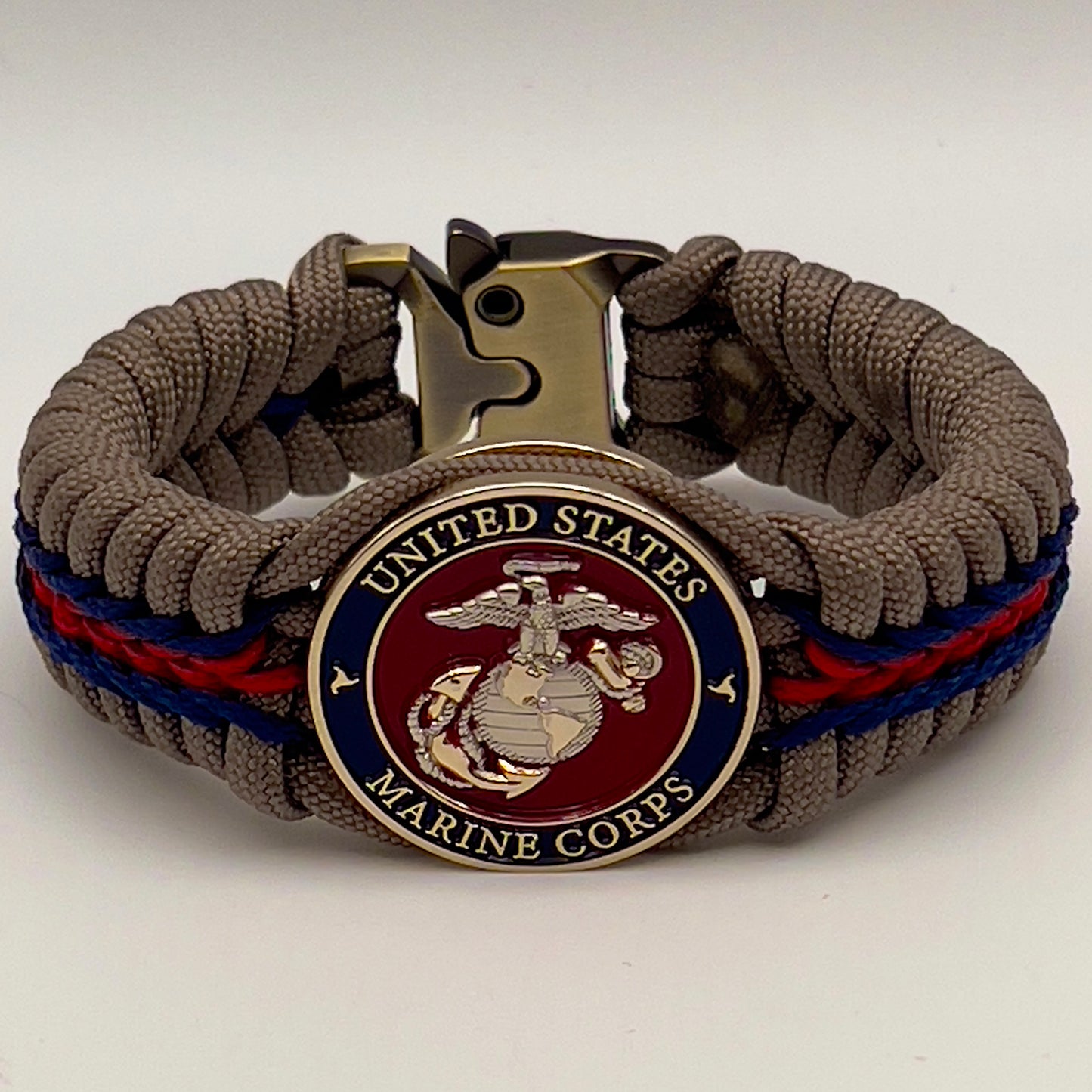 Thick, semi-rigid and comfortable braided United States Marine Corps bracelet featuring a 24K gold and silver plated USMC officer Eagle Globe and Anchor medallion, a gold Cobra style tactical buckle and woven with tan 550 paracord and Imperial red and gold micro cord.