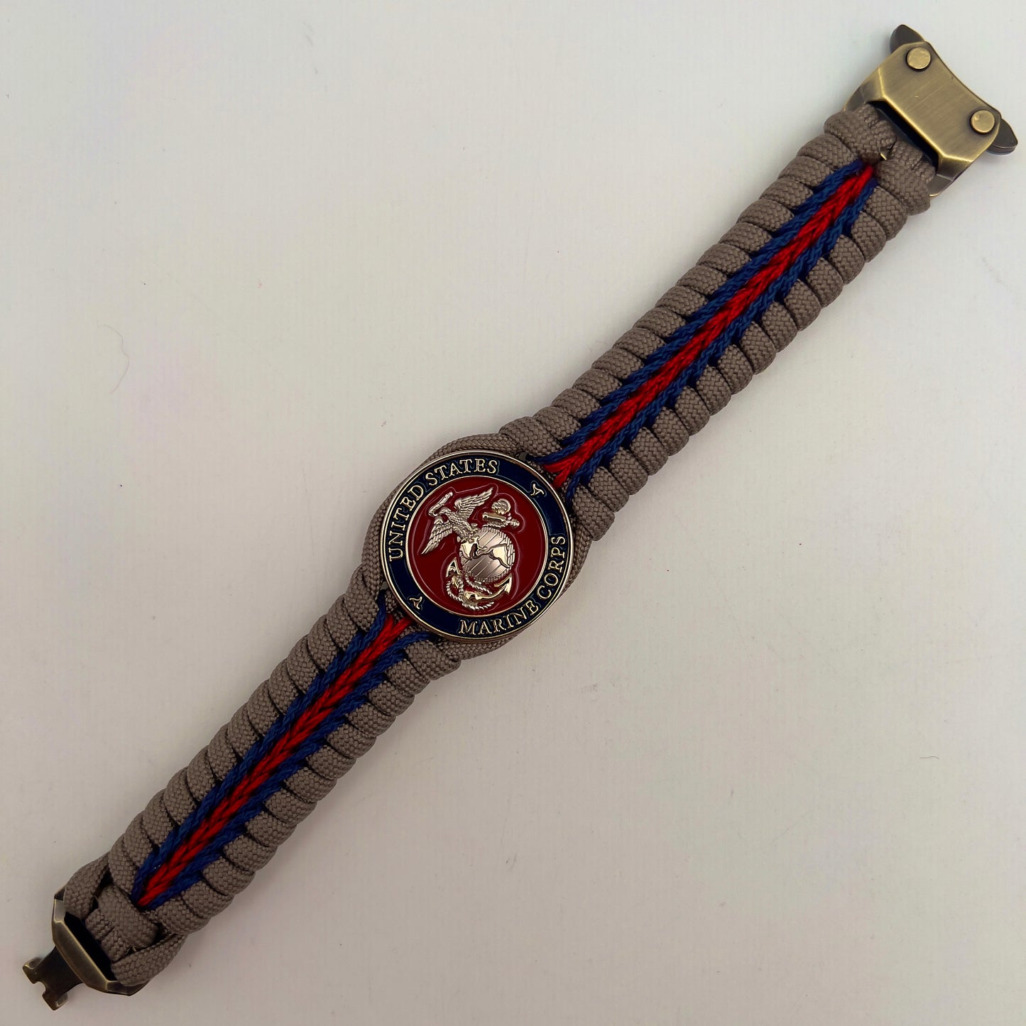 Thick, semi-rigid and comfortable braided United States Marine Corps bracelet featuring a 24K gold and silver plated USMC officer Eagle Globe and Anchor medallion, a gold Cobra style tactical buckle and woven with tan 550 paracord and Imperial red and gold micro cord.
