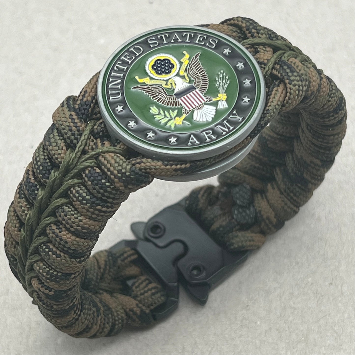Thick, narrow, rigid and comfortable braided United States Army bracelet featuring an antique silver plated baked enamel hand painted US Army medallion, a black Cobra style tactical buckle and woven with Woodland Camo 550 paracord and Olive Drab micro cord.