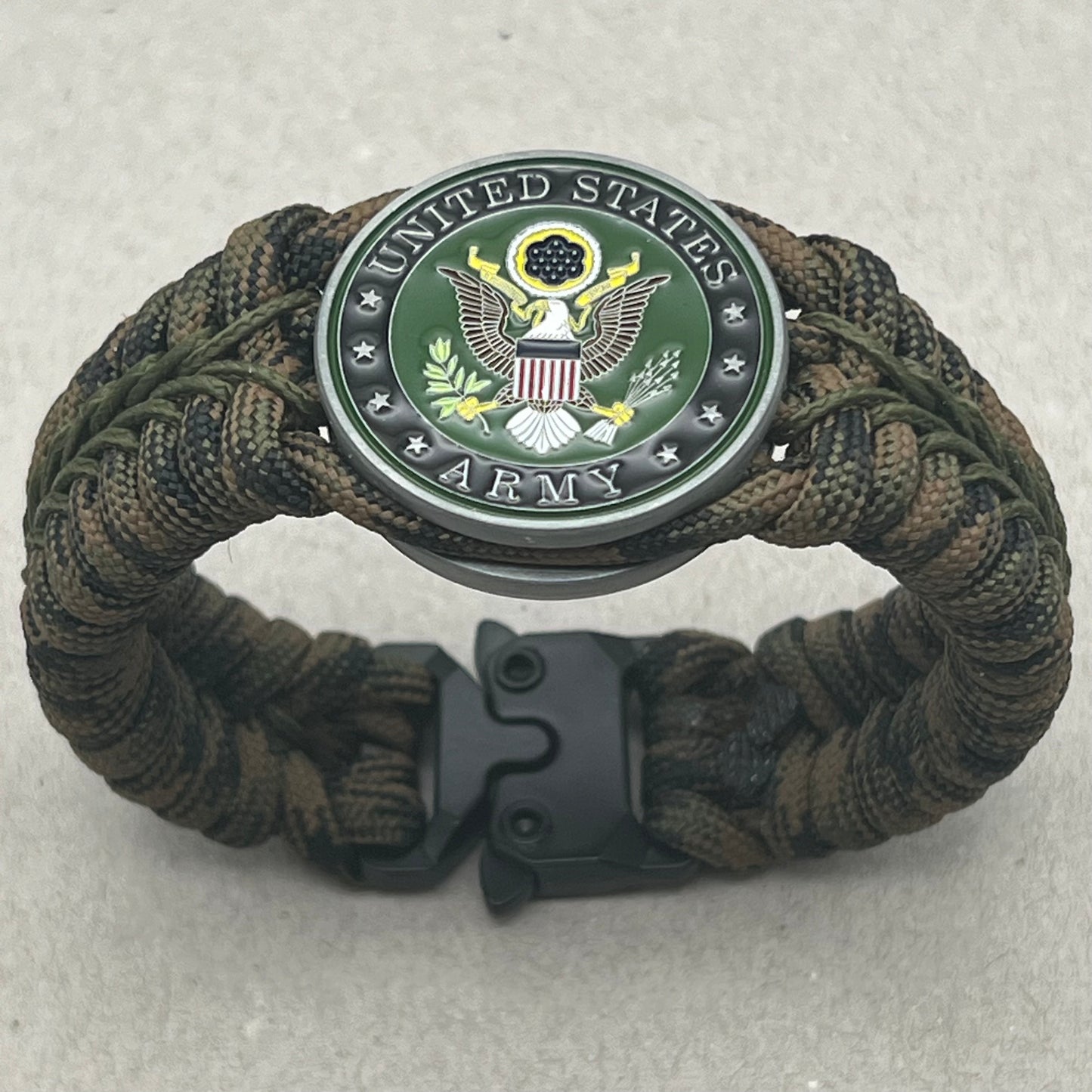 Thick, narrow, rigid and comfortable braided United States Army bracelet featuring an antique silver plated baked enamel hand painted US Army medallion, a black Cobra style tactical buckle and woven with Woodland Camo 550 paracord and Olive Drab micro cord.