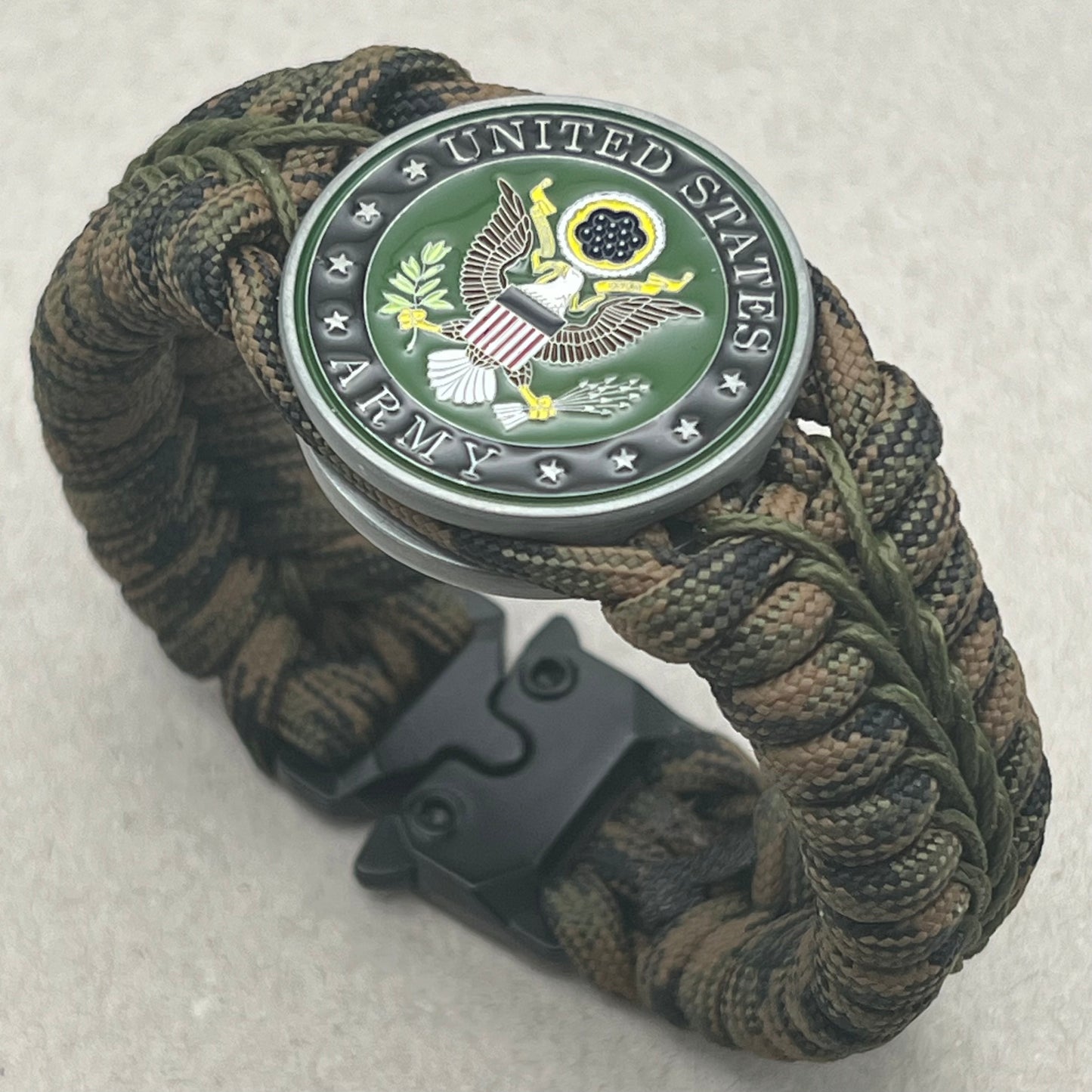 Thick, narrow, rigid and comfortable braided United States Army bracelet featuring an antique silver plated baked enamel hand painted US Army medallion, a black Cobra style tactical buckle and woven with Woodland Camo 550 paracord and Olive Drab micro cord.