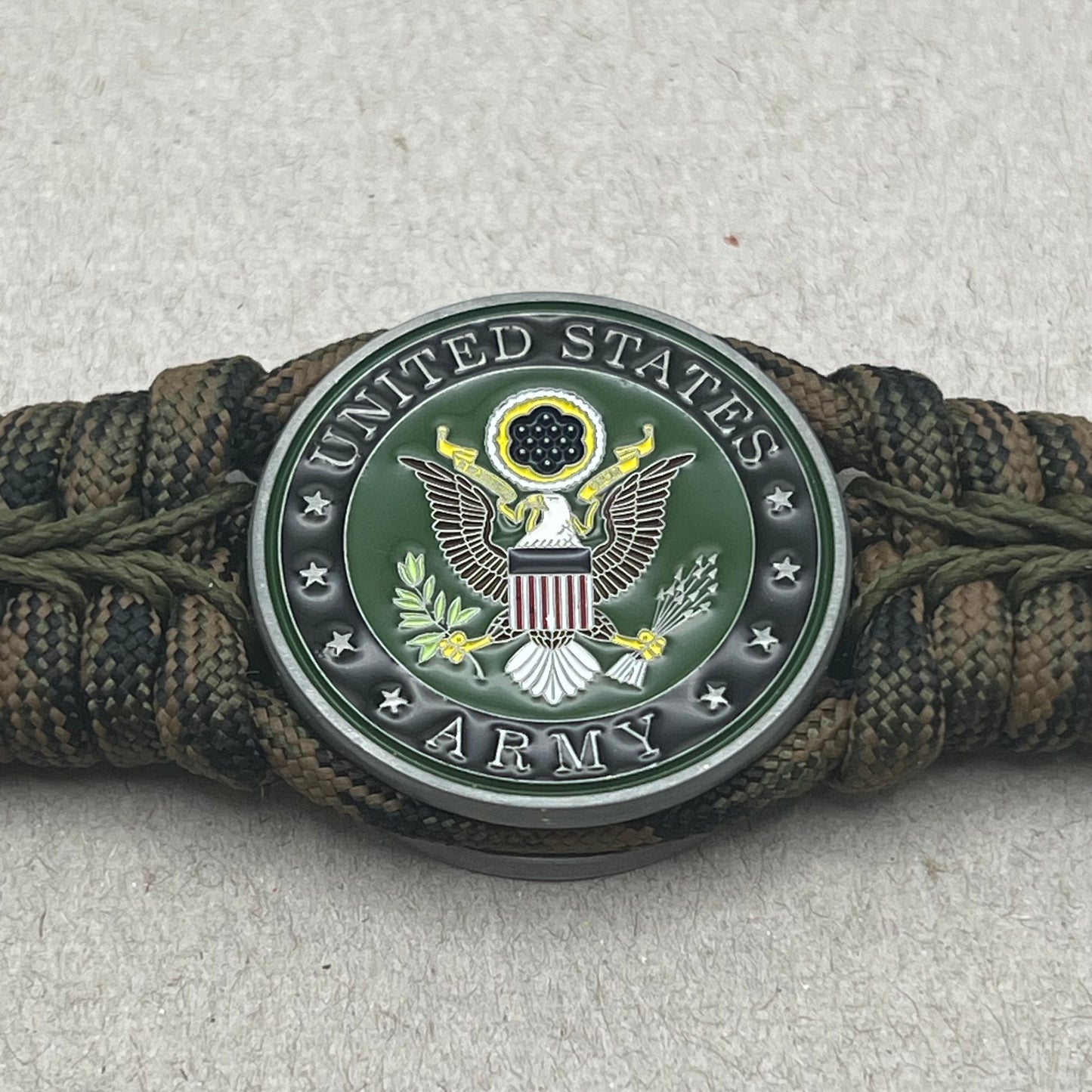 Thick, narrow, rigid and comfortable braided United States Army bracelet featuring an antique silver plated baked enamel hand painted US Army medallion, a black Cobra style tactical buckle and woven with Woodland Camo 550 paracord and Olive Drab micro cord.