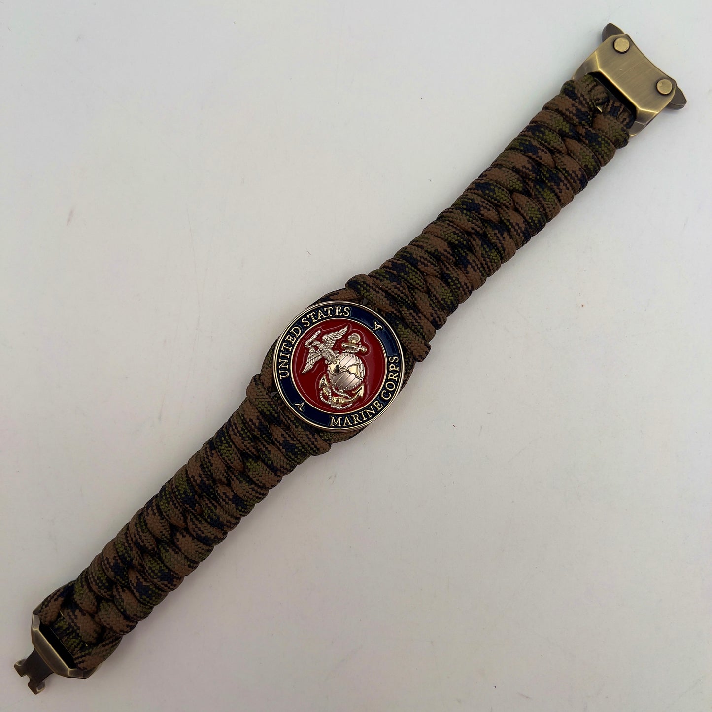 Thick, semi-rigid and comfortable braided United States Marine Corps bracelet featuring a 24K gold and silver plated USMC officer Eagle Globe and Anchor medallion, a gold Cobra style tactical buckle and woven with Woodland Camo 550 paracord.