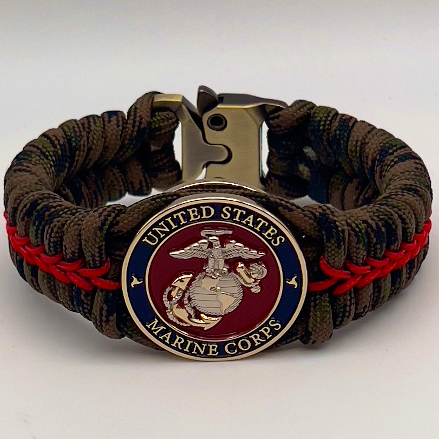 Thick, semi-rigid and comfortable braided United States Marine Corps bracelet featuring a 24K gold and silver plated USMC officer Eagle Globe and Anchor medallion, a gold Cobra style tactical buckle and woven with Woodland Camo 550 paracord and Imperial Red micro cord.