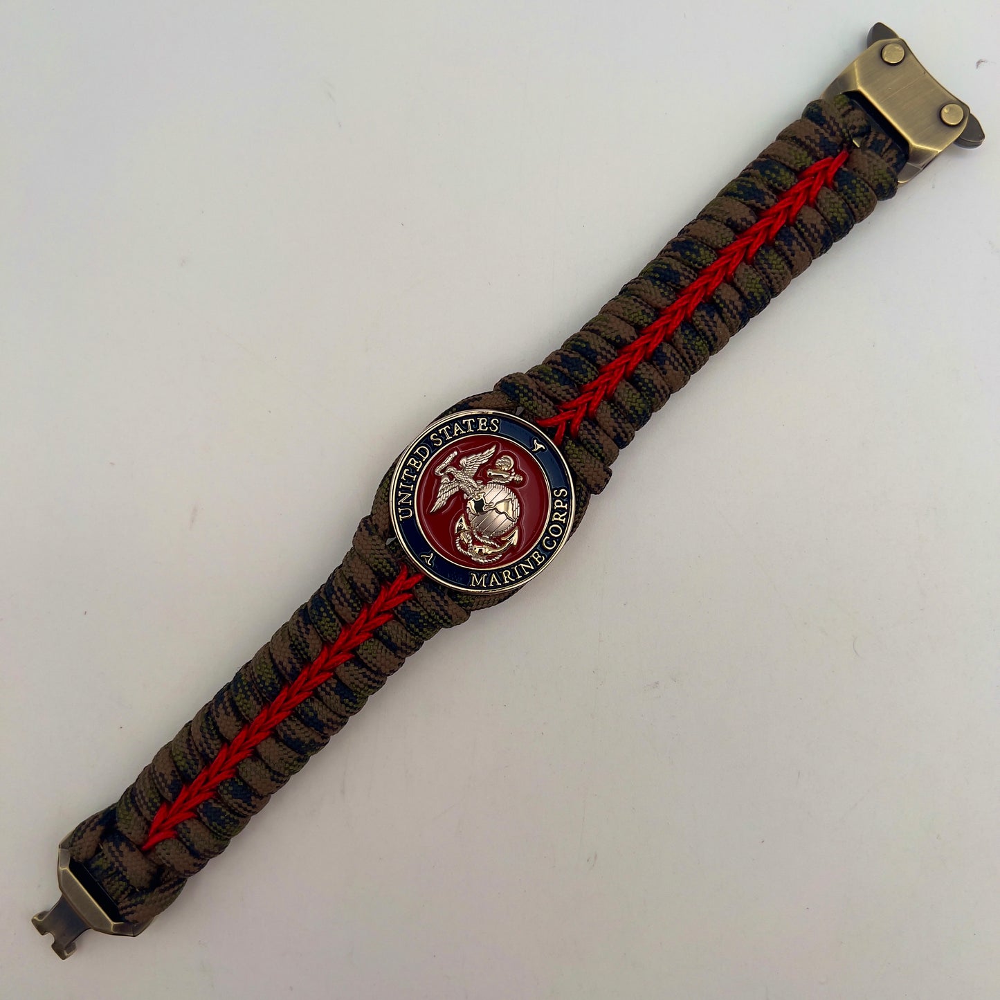 Thick, semi-rigid and comfortable braided United States Marine Corps bracelet featuring a 24K gold and silver plated USMC officer Eagle Globe and Anchor medallion, a gold Cobra style tactical buckle and woven with Woodland Camo 550 paracord and Imperial Red micro cord.