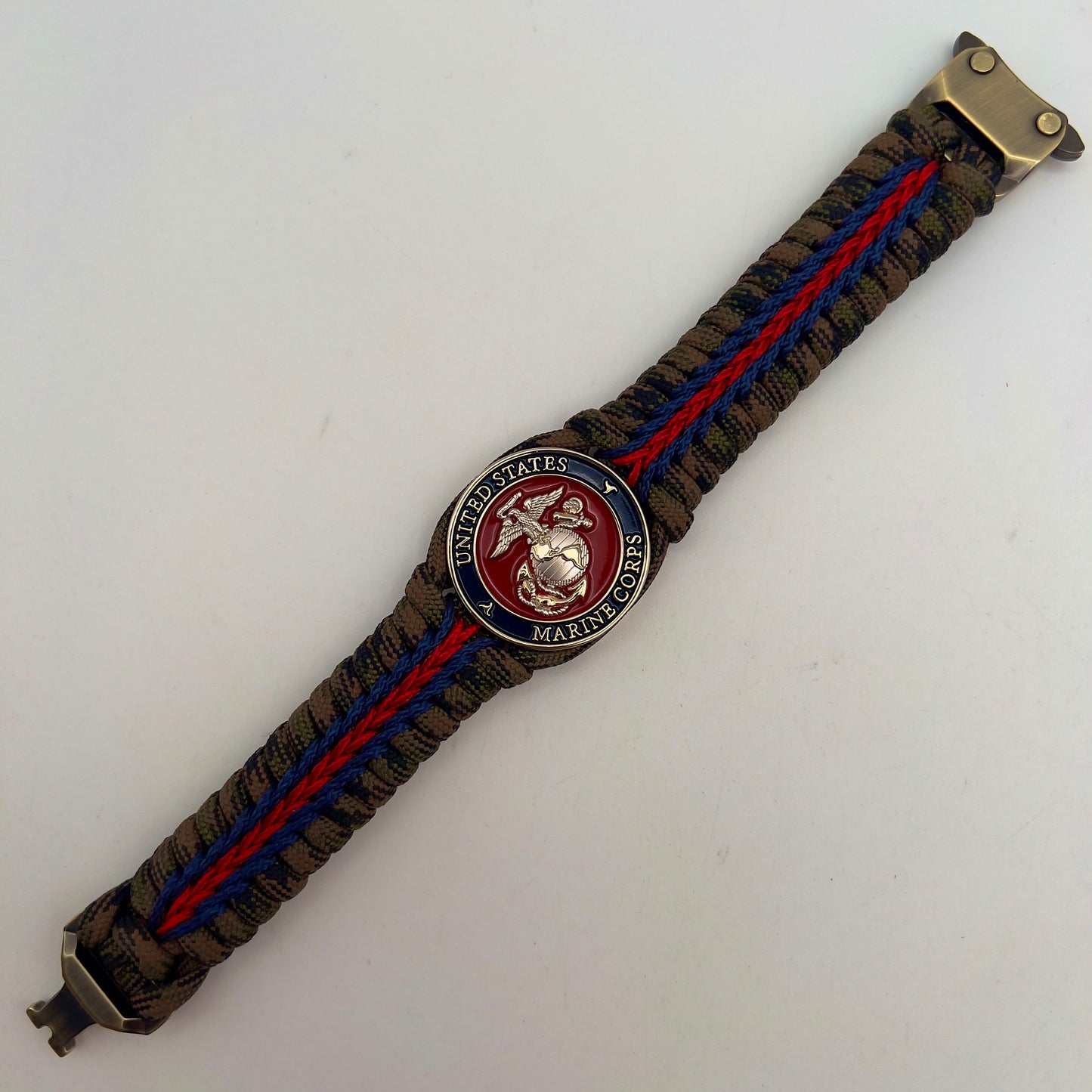 Thick, semi-rigid and comfortable braided United States Marine Corps bracelet featuring a 24K gold and silver plated USMC officer Eagle Globe and Anchor medallion, a gold Cobra style tactical buckle and woven with Woodland Camo 550 paracord and Imperial Red and Navy Blue micro cord.
