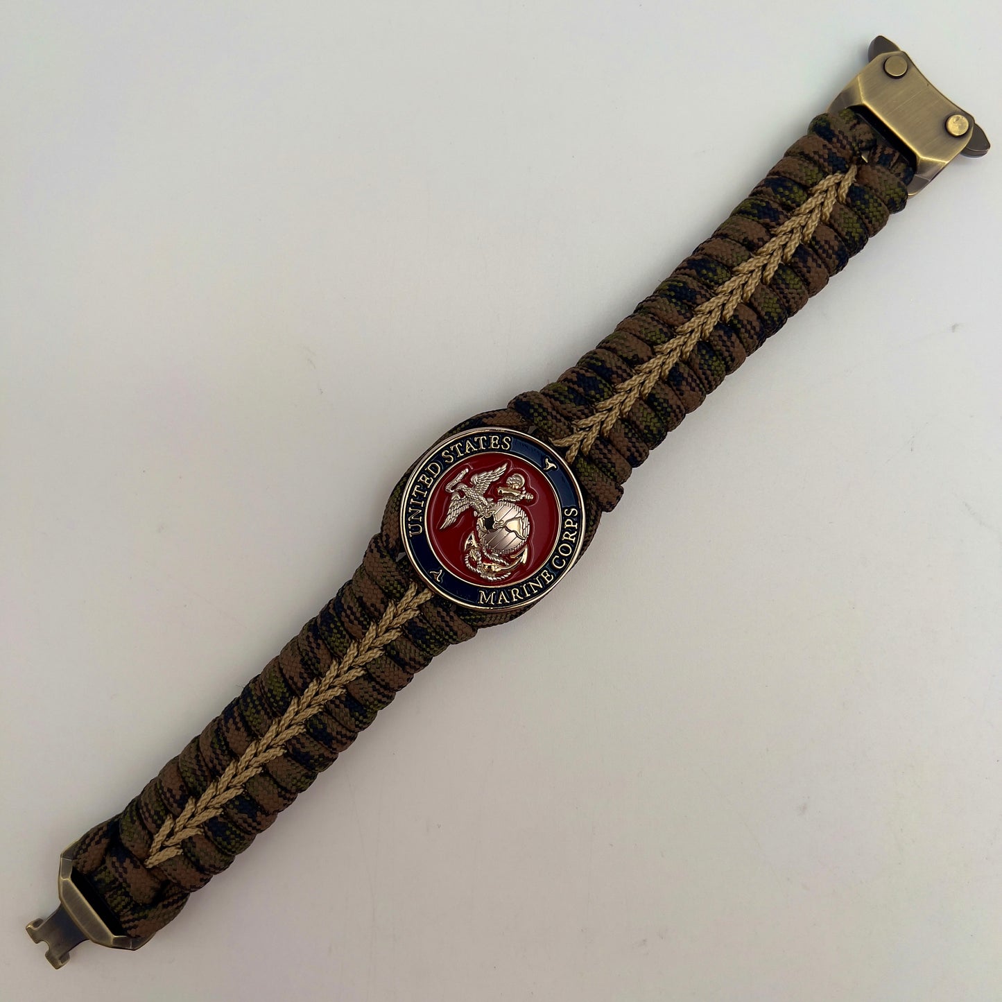 Thick, semi-rigid and comfortable braided United States Marine Corps bracelet featuring a 24K gold and silver plated USMC officer Eagle Globe and Anchor medallion, a gold Cobra style tactical buckle and woven with Woodland Camo 550 paracord and gold micro cord.