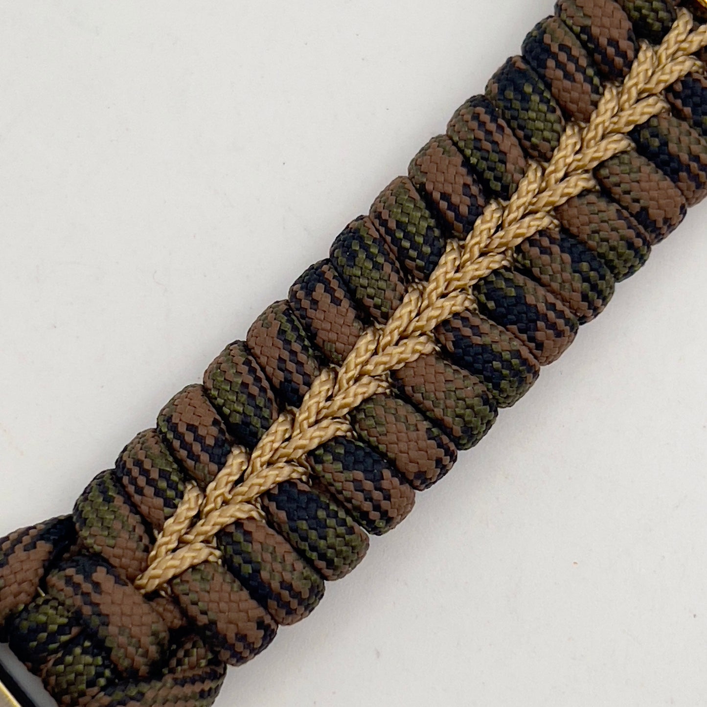 Thick, semi-rigid and comfortable braided United States Marine Corps bracelet featuring a 24K gold and silver plated USMC officer Eagle Globe and Anchor medallion, a gold Cobra style tactical buckle and woven with Woodland Camo 550 paracord and gold micro cord.