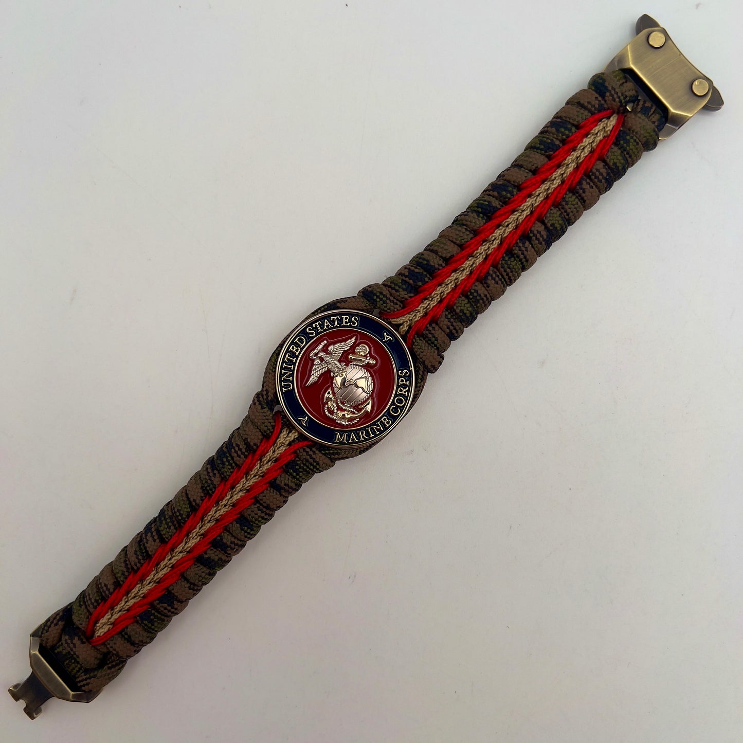 Thick, semi-rigid and comfortable braided United States Marine Corps bracelet featuring a 24K gold and silver plated USMC officer Eagle Globe and Anchor medallion, a gold Cobra style tactical buckle and woven with Woodland Camo 550 paracord and Imperial Red and gold micro cord.