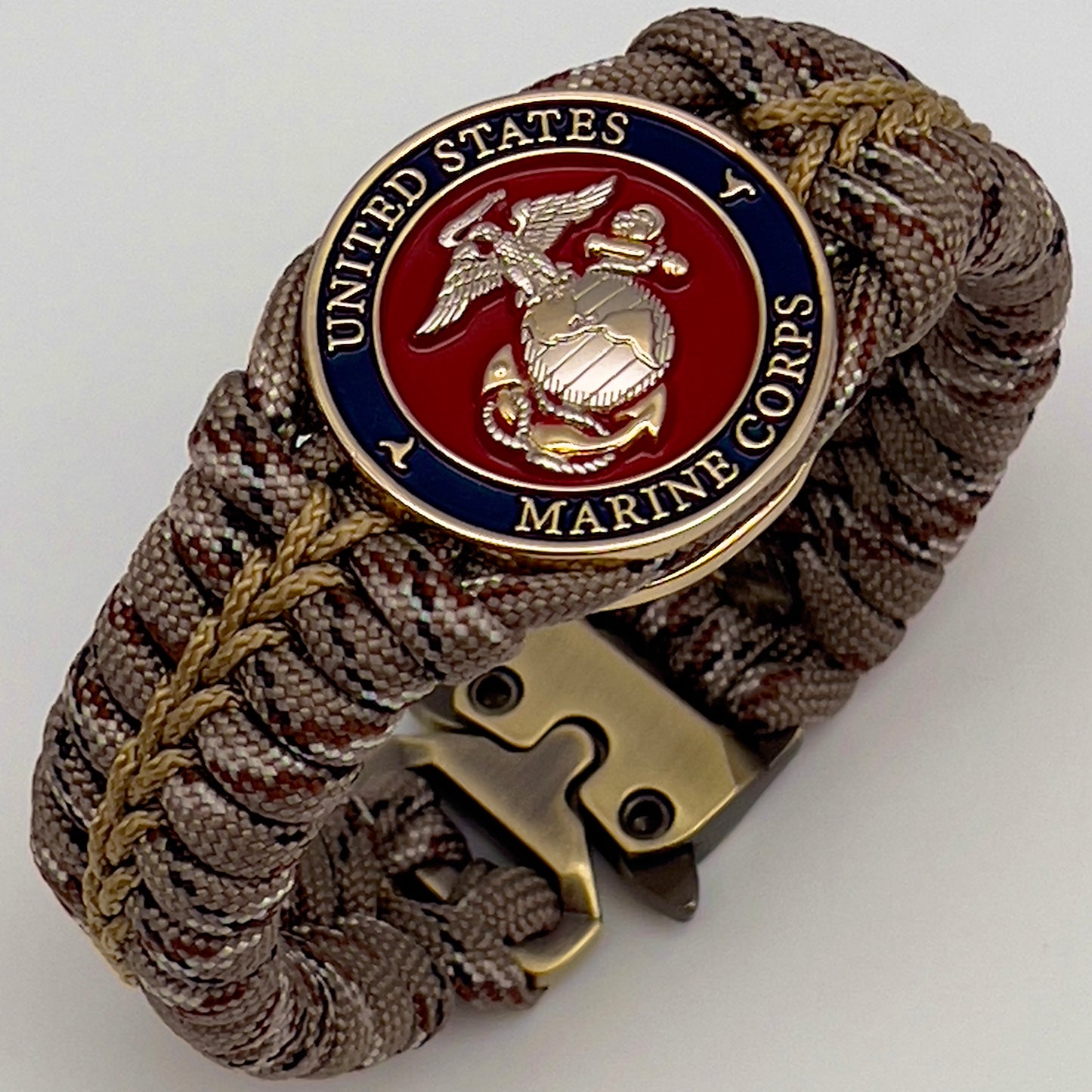 Thick and comfortable braided United States Marine Corps bracelet featuring a 24K gold and silver plated USMC officer Eagle Globe and Anchor medallion, a Cobra style tactical buckle and woven with Desert Camo 550 paracord gold micro cord.