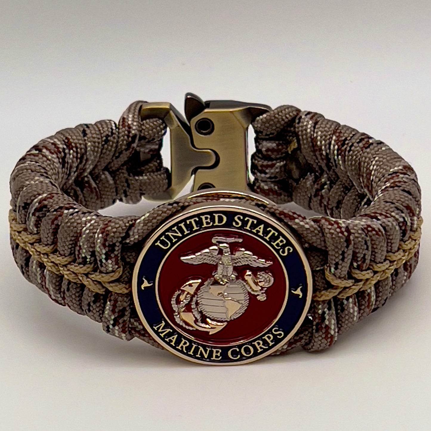 Thick and comfortable braided United States Marine Corps bracelet featuring a 24K gold and silver plated USMC officer Eagle Globe and Anchor medallion, a Cobra style tactical buckle and woven with Desert Camo 550 paracord gold micro cord.