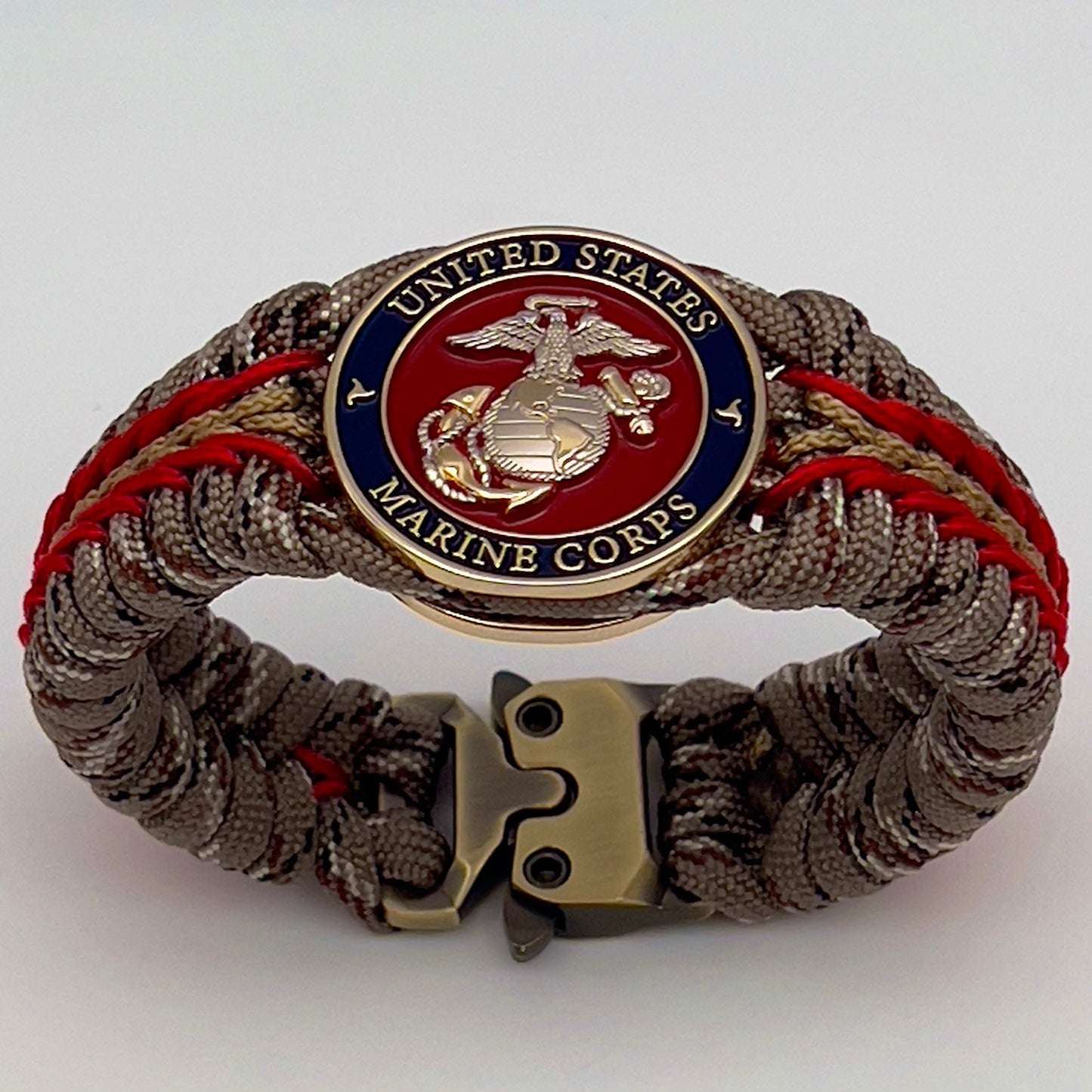 Thick and comfortable braided United States Marine Corps bracelet featuring a 24K gold and silver plated USMC officer Eagle Globe and Anchor medallion, a Cobra style tactical buckle and woven with Desert Camo 550 paracord and Imperial red and gold micro cord.
