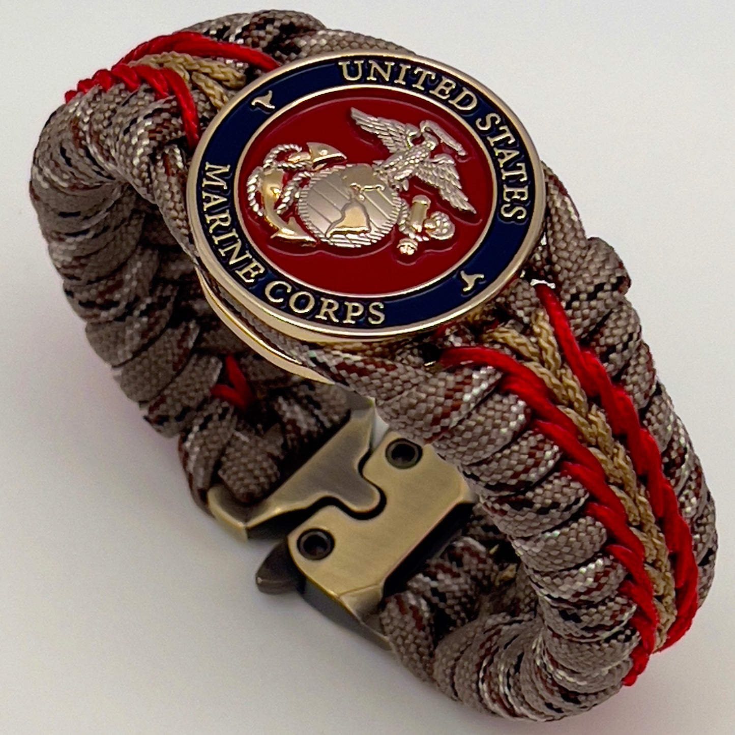Thick and comfortable braided United States Marine Corps bracelet featuring a 24K gold and silver plated USMC officer Eagle Globe and Anchor medallion, a Cobra style tactical buckle and woven with Desert Camo 550 paracord and Imperial red and gold micro cord.