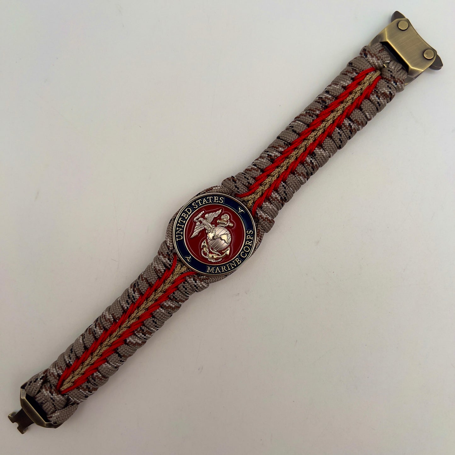 Thick and comfortable braided United States Marine Corps bracelet featuring a 24K gold and silver plated USMC officer Eagle Globe and Anchor medallion, a Cobra style tactical buckle and woven with Desert Camo 550 paracord and Imperial red and gold micro cord.
