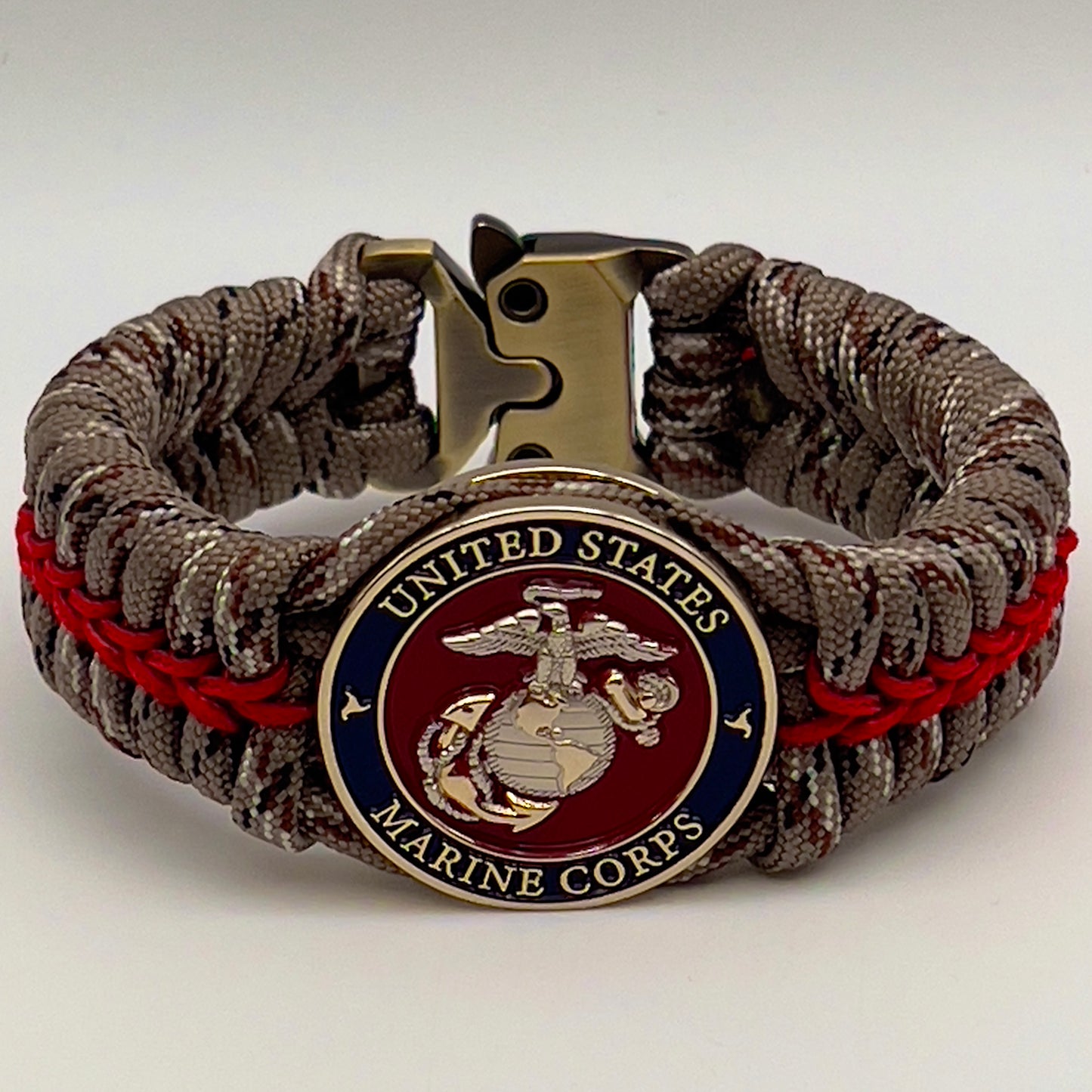 Thick and comfortable braided United States Marine Corps bracelet featuring a 24K gold and silver plated USMC officer Eagle Globe and Anchor medallion, a Cobra style tactical buckle and woven with Desert Camo 550 paracord and Imperial red micro cord.