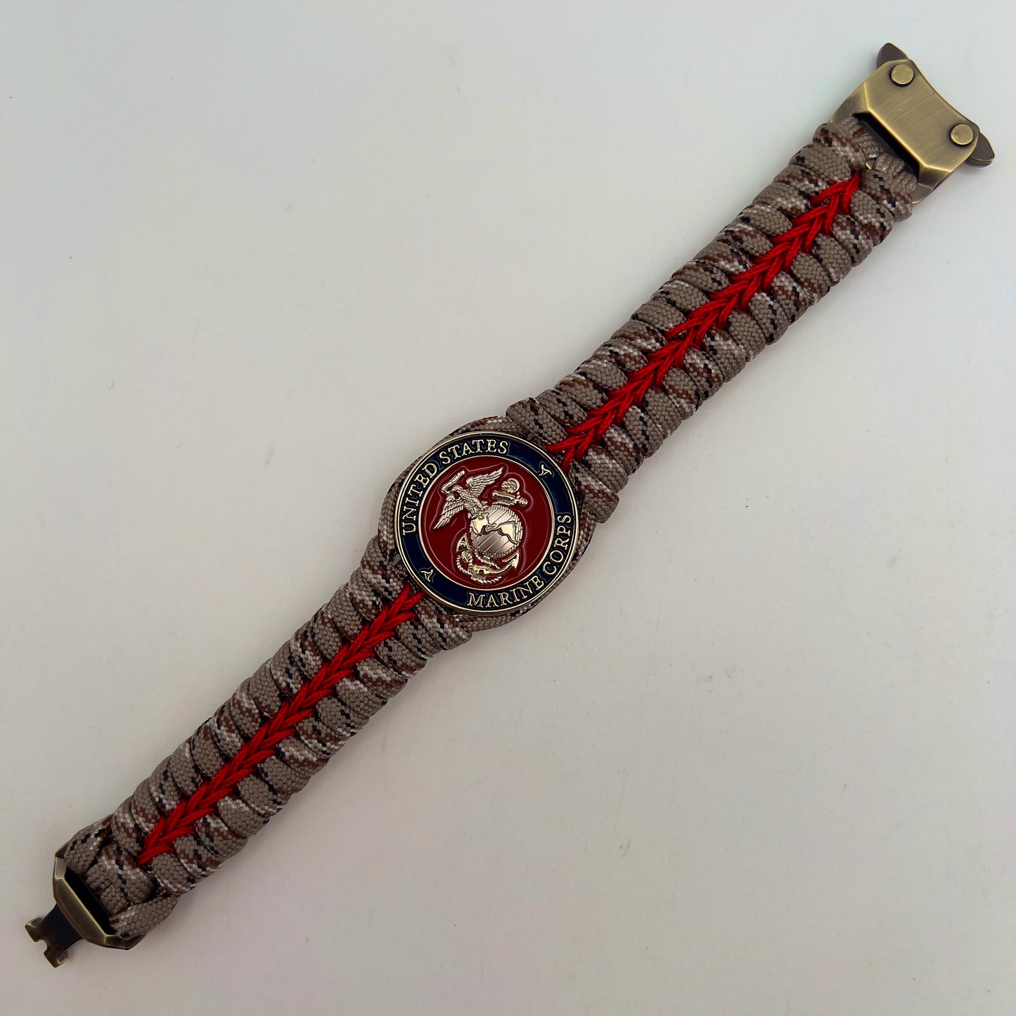 Thick and comfortable braided United States Marine Corps bracelet featuring a 24K gold and silver plated USMC officer Eagle Globe and Anchor medallion, a Cobra style tactical buckle and woven with Desert Camo 550 paracord and Imperial red micro cord.