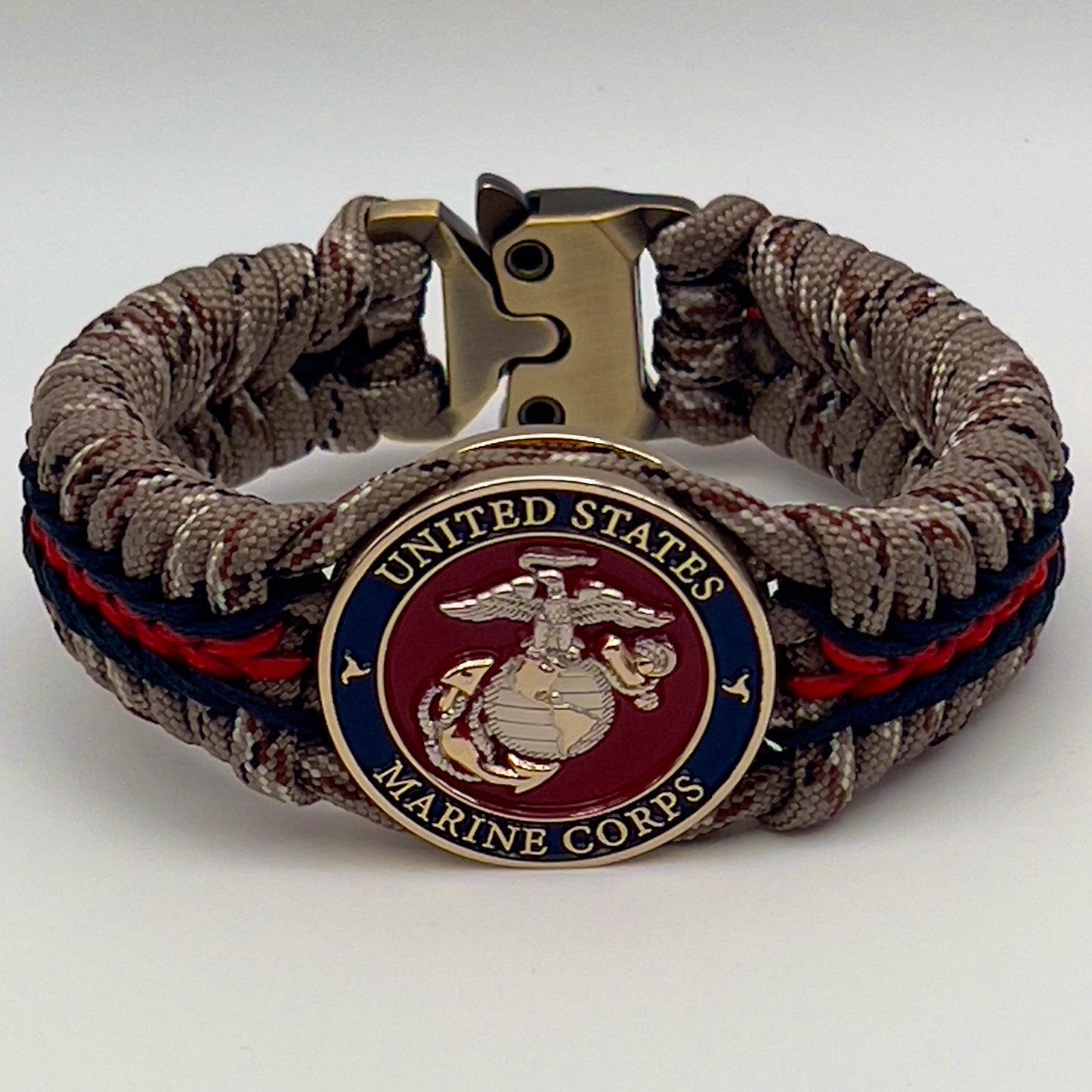 Thick and comfortable braided United States Marine Corps bracelet featuring a 24K gold and silver plated USMC officer Eagle Globe and Anchor medallion, a Cobra style tactical buckle and woven with Desert Camo 550 paracord and Imperial red and black micro cord.