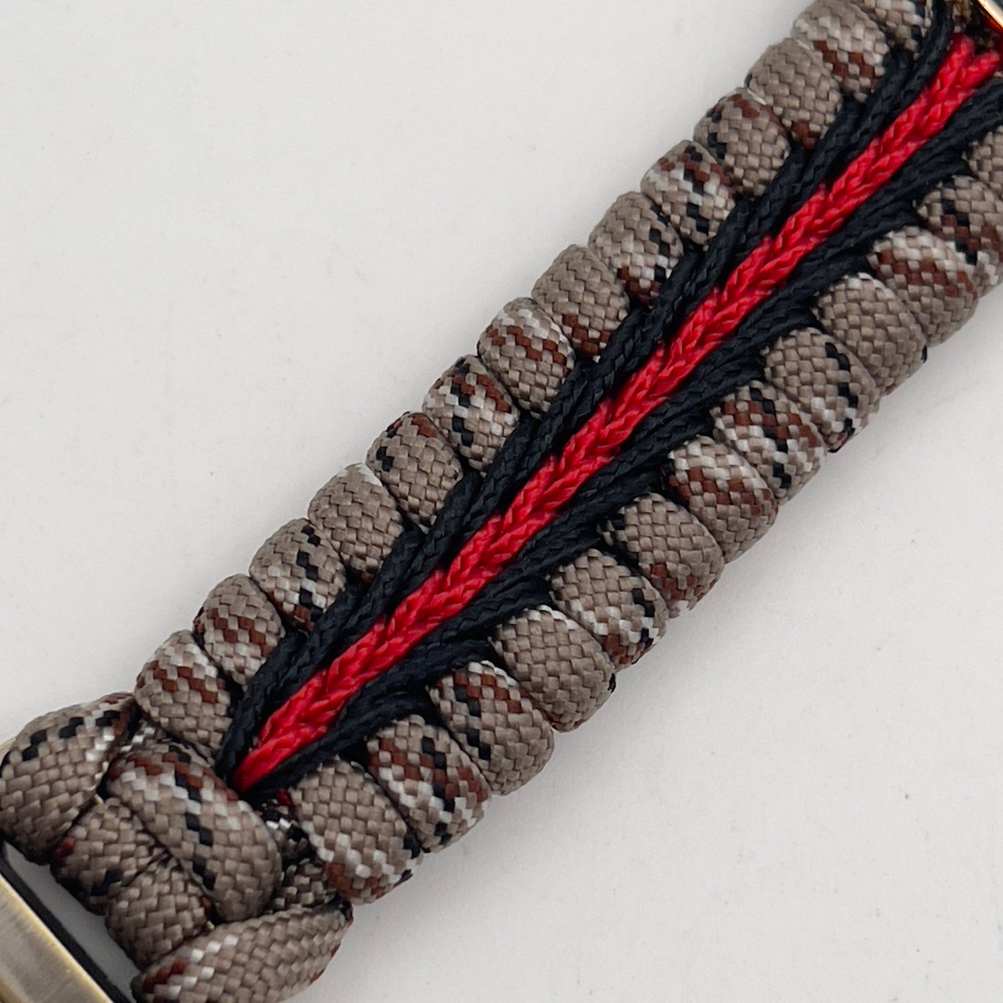Thick and comfortable braided United States Marine Corps bracelet featuring a 24K gold and silver plated USMC officer Eagle Globe and Anchor medallion, a Cobra style tactical buckle and woven with Desert Camo 550 paracord and Imperial red and black micro cord.