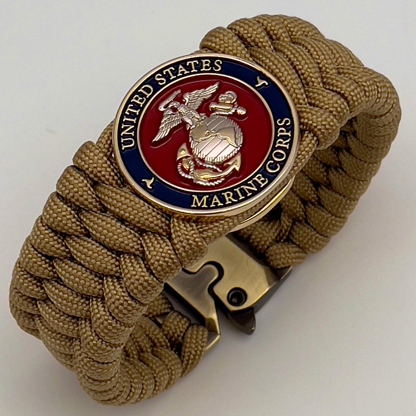 Thick and comfortable braided United States Marine Corps bracelet featuring a 24K gold and silver plated USMC officer Eagle Globe and Anchor medallion, a Cobra style tactical buckle and woven with gold 550 paracord.