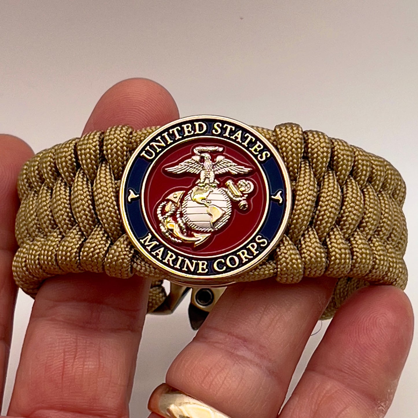 Thick and comfortable braided United States Marine Corps bracelet featuring a 24K gold and silver plated USMC officer Eagle Globe and Anchor medallion, a Cobra style tactical buckle and woven with gold 550 paracord.