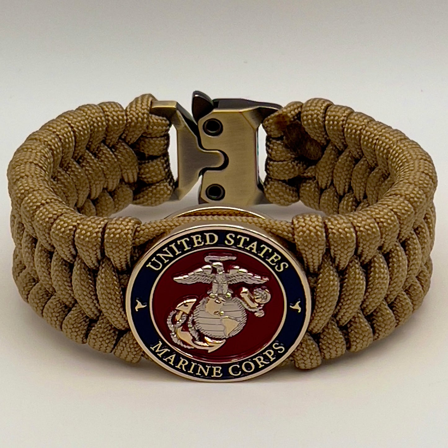 Thick and comfortable braided United States Marine Corps bracelet featuring a 24K gold and silver plated USMC officer Eagle Globe and Anchor medallion, a Cobra style tactical buckle and woven with gold 550 paracord.