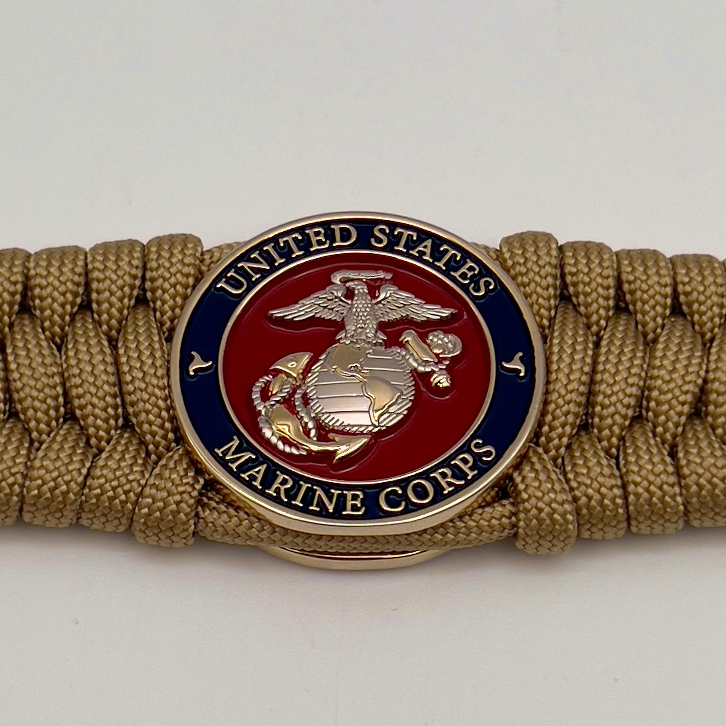 Thick and comfortable braided United States Marine Corps bracelet featuring a 24K gold and silver plated USMC officer Eagle Globe and Anchor medallion, a Cobra style tactical buckle and woven with gold 550 paracord.