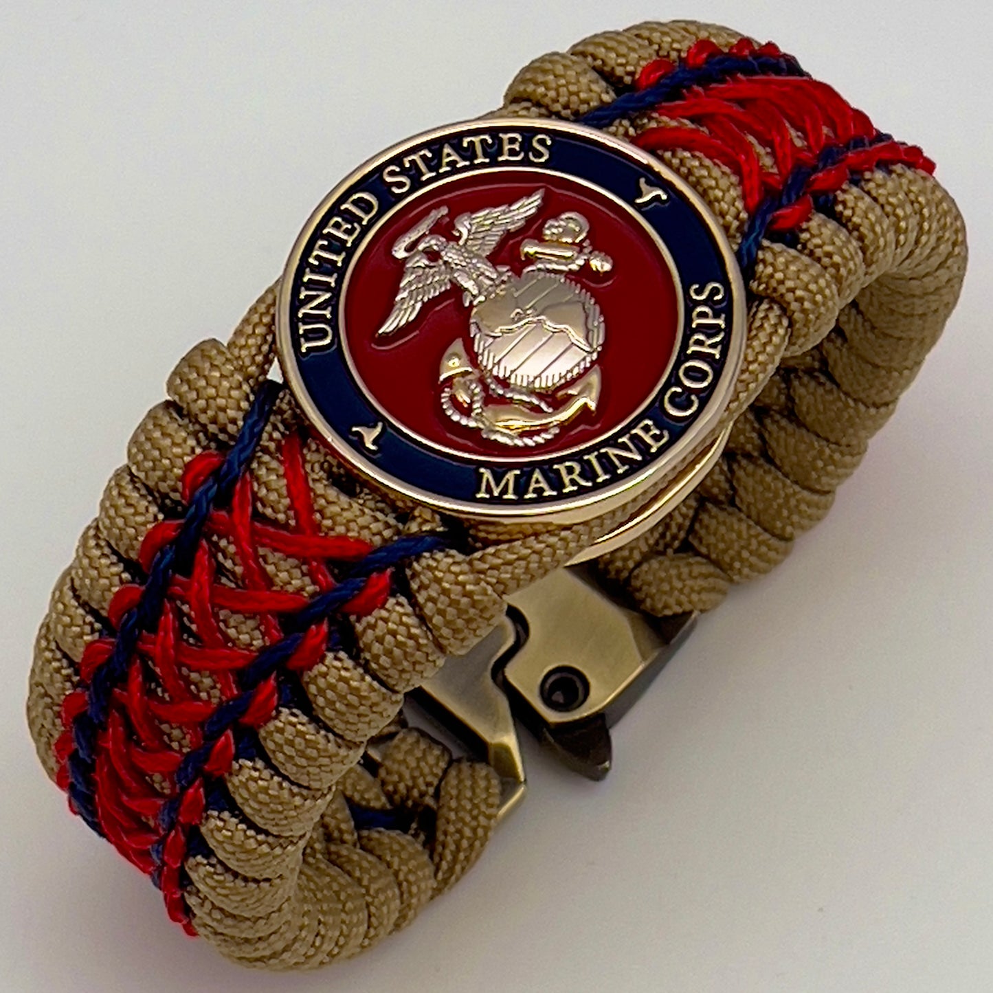 Thick and comfortable braided United States Marine Corps bracelet featuring a 24K gold and silver plated USMC officer Eagle Globe and Anchor medallion, a gold Cobra style tactical buckle and woven with gold 550 paracord and Imperial Red and Navy Blue micro cord.
