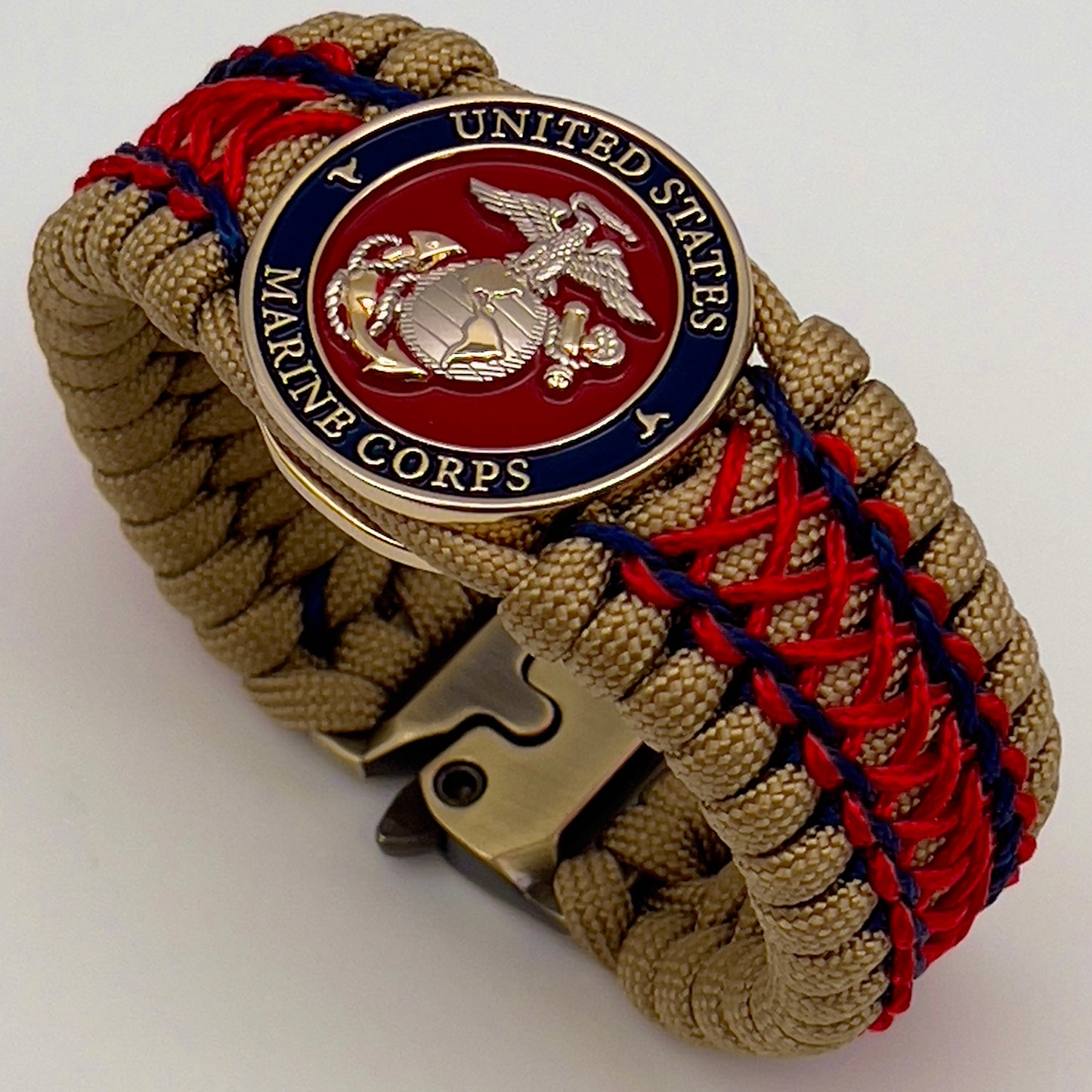 Thick and comfortable braided United States Marine Corps bracelet featuring a 24K gold and silver plated USMC officer Eagle Globe and Anchor medallion, a gold Cobra style tactical buckle and woven with gold 550 paracord and Imperial Red and Navy Blue micro cord.