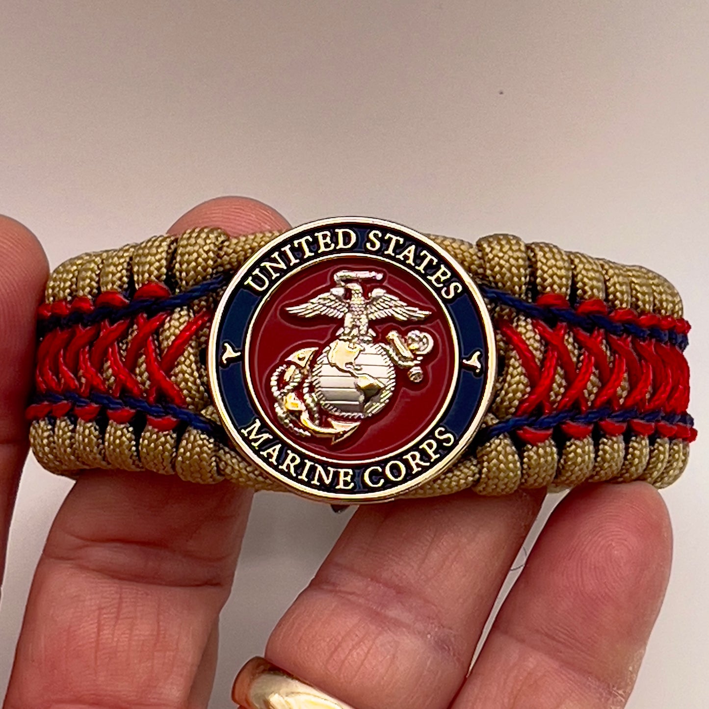Thick and comfortable braided United States Marine Corps bracelet featuring a 24K gold and silver plated USMC officer Eagle Globe and Anchor medallion, a gold Cobra style tactical buckle and woven with gold 550 paracord and Imperial Red and Navy Blue micro cord.