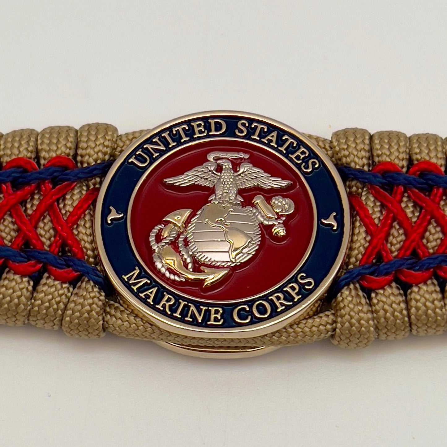 Thick and comfortable braided United States Marine Corps bracelet featuring a 24K gold and silver plated USMC officer Eagle Globe and Anchor medallion, a gold Cobra style tactical buckle and woven with gold 550 paracord and Imperial Red and Navy Blue micro cord.