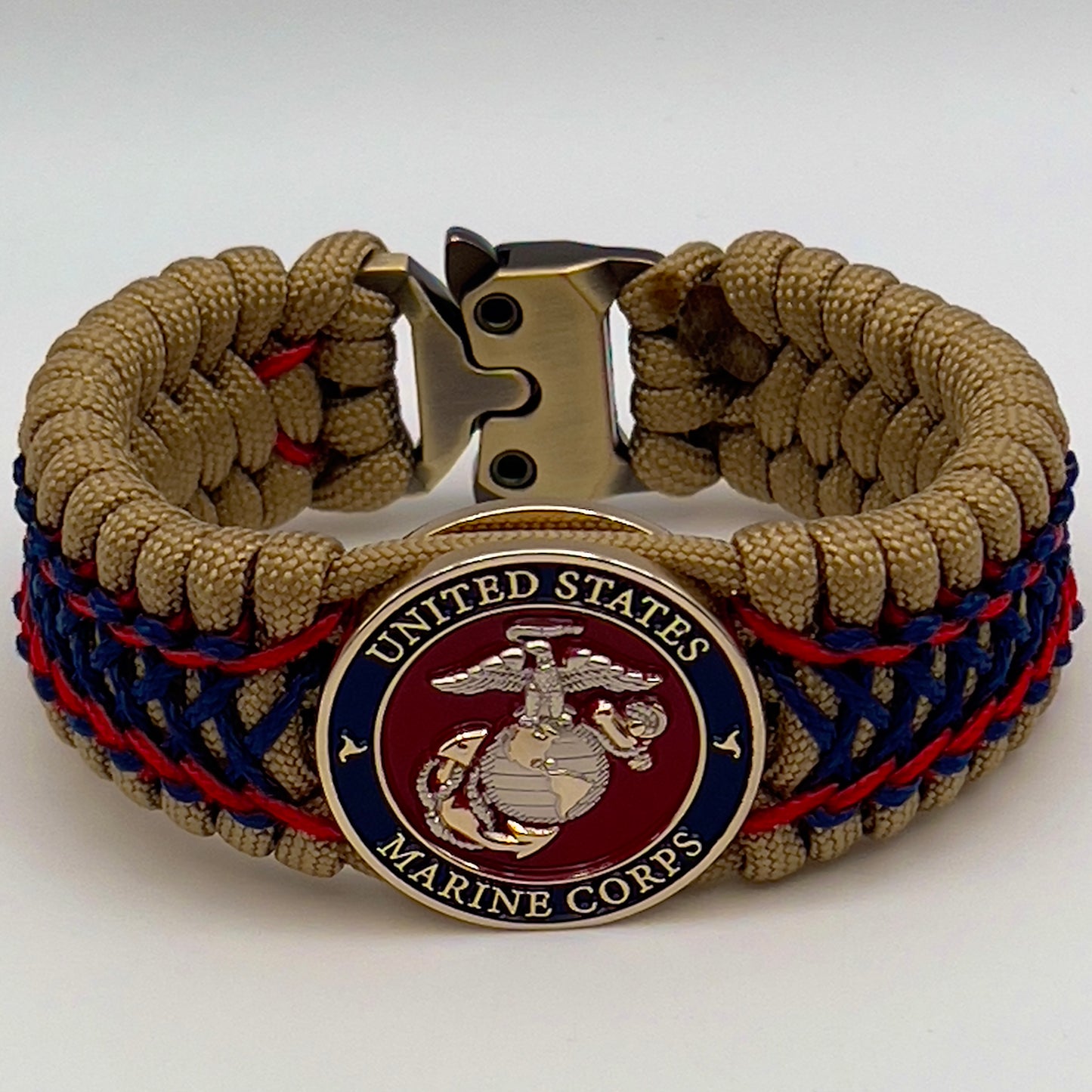 Thick and comfortable braided United States Marine Corps bracelet featuring a 24K gold and silver plated USMC officer Eagle Globe and Anchor medallion, a gold Cobra style tactical buckle and woven with gold 550 paracord and Imperial Red and Navy Blue micro cord.