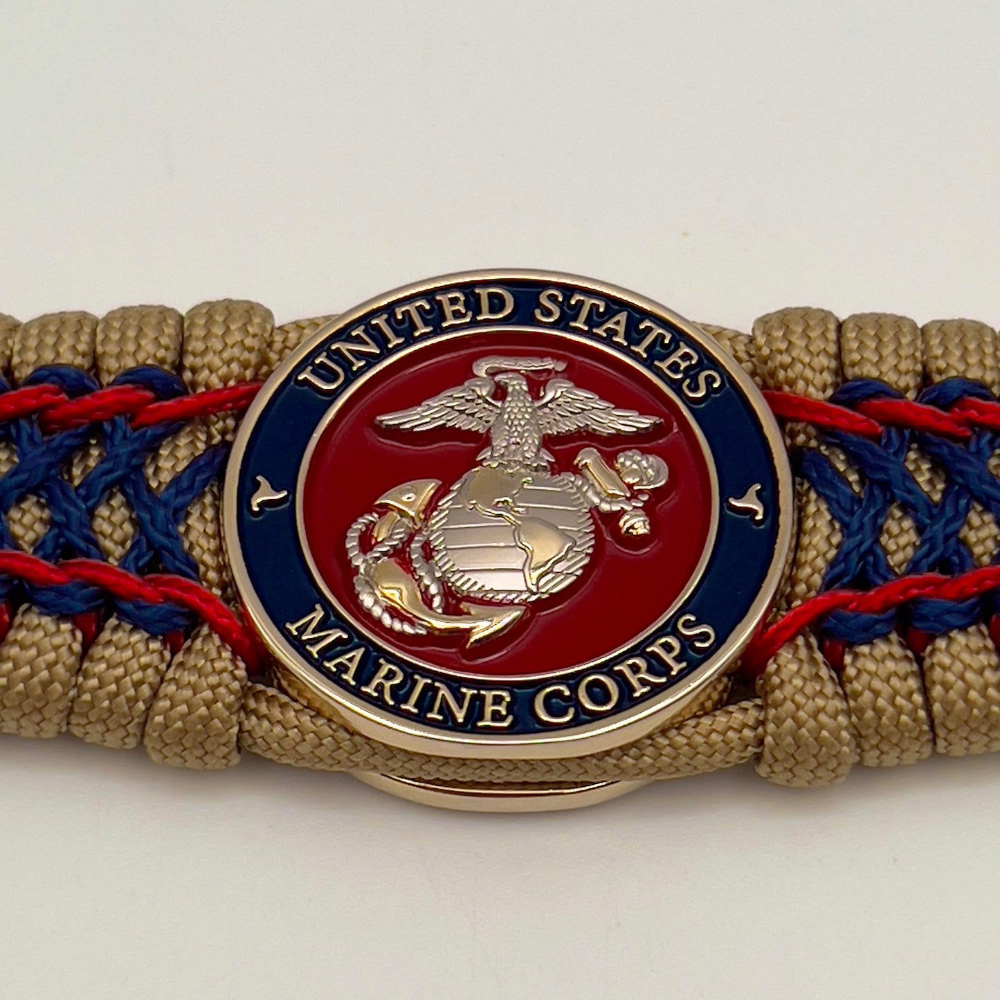 Thick and comfortable braided United States Marine Corps bracelet featuring a 24K gold and silver plated USMC officer Eagle Globe and Anchor medallion, a gold Cobra style tactical buckle and woven with gold 550 paracord and Imperial Red and Navy Blue micro cord.