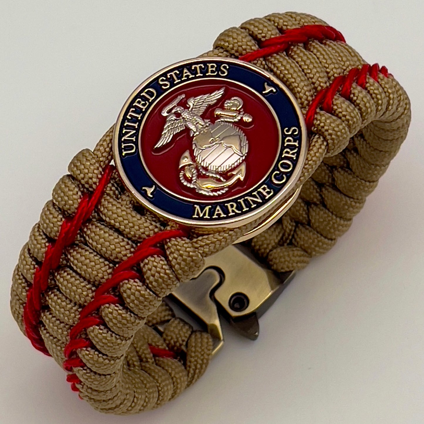 Thick and comfortable braided United States Marine Corps bracelet featuring a 24K gold and silver plated USMC officer Eagle Globe and Anchor medallion, a gold Cobra style tactical buckle and woven with gold 550 paracord and Imperial Red micro cord.