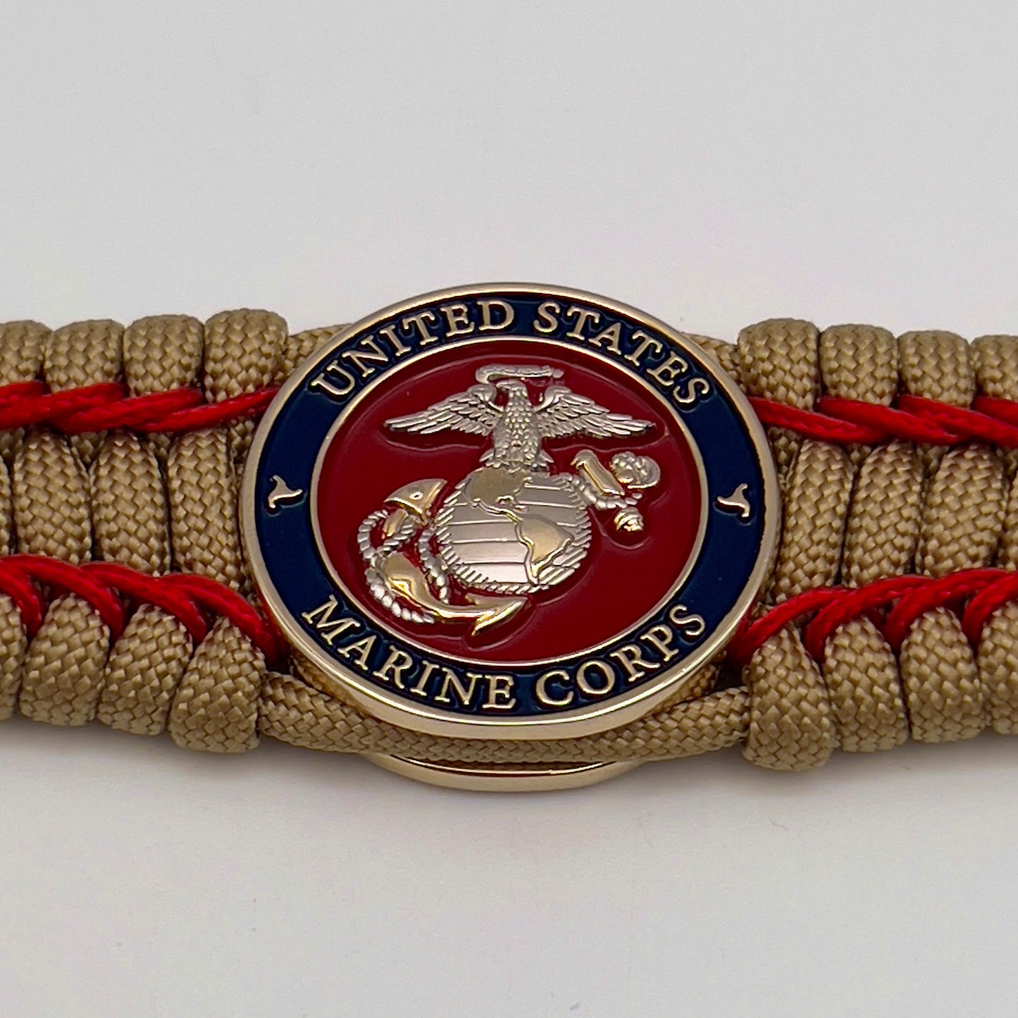 Thick and comfortable braided United States Marine Corps bracelet featuring a 24K gold and silver plated USMC officer Eagle Globe and Anchor medallion, a gold Cobra style tactical buckle and woven with gold 550 paracord and Imperial Red micro cord.