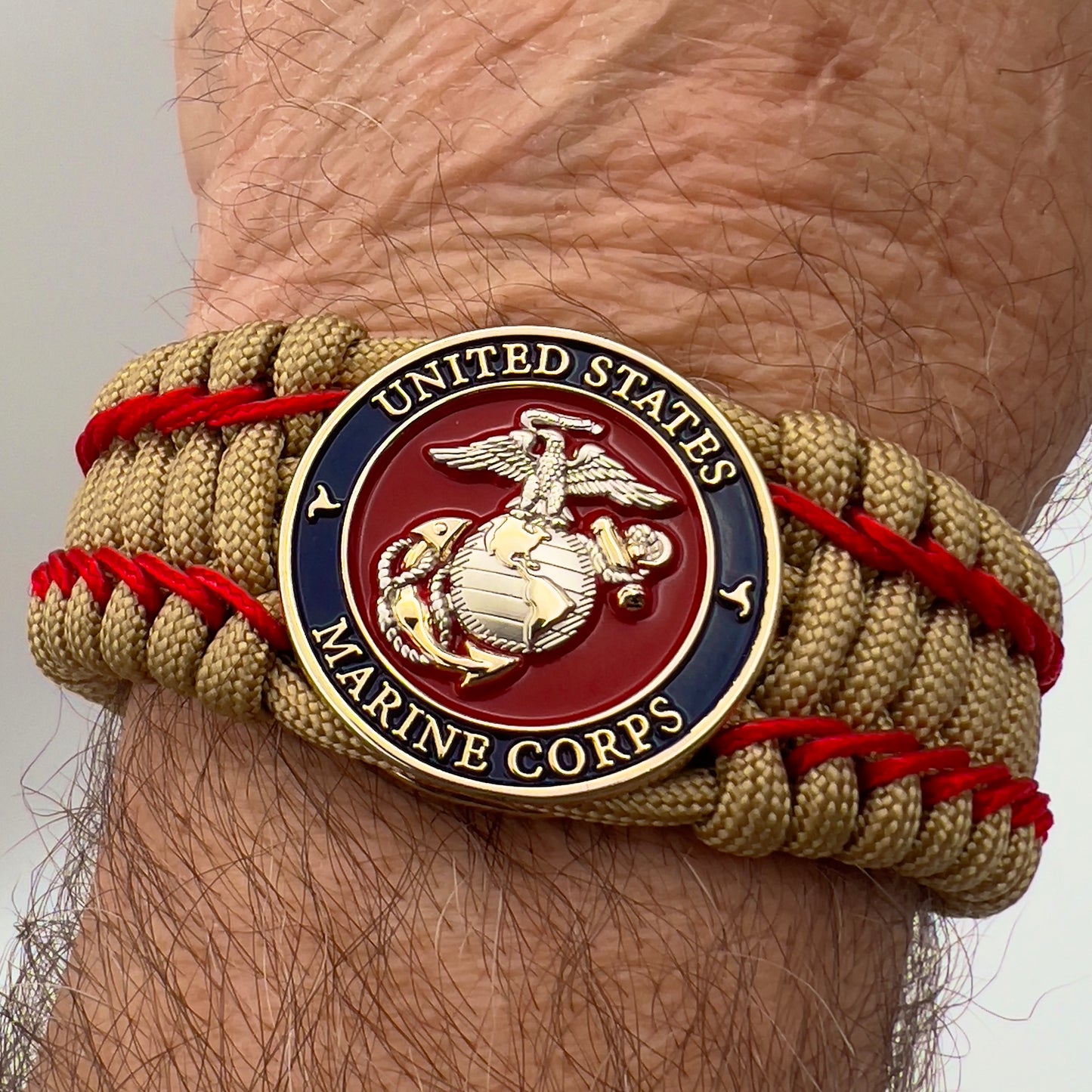Thick and comfortable braided United States Marine Corps bracelet featuring a 24K gold and silver plated USMC officer Eagle Globe and Anchor medallion, a gold Cobra style tactical buckle and woven with gold 550 paracord and Imperial Red micro cord.