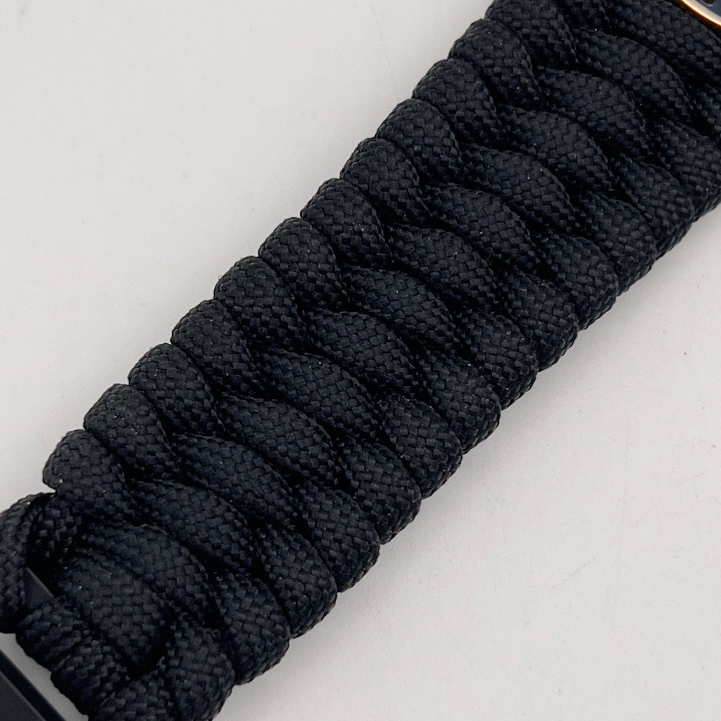 Thick and comfortable braided United States Marine Corps bracelet featuring a 24K gold and silver plated USMC officer Eagle Globe and Anchor medallion, a black Cobra style tactical buckle and woven with black 550 paracord.