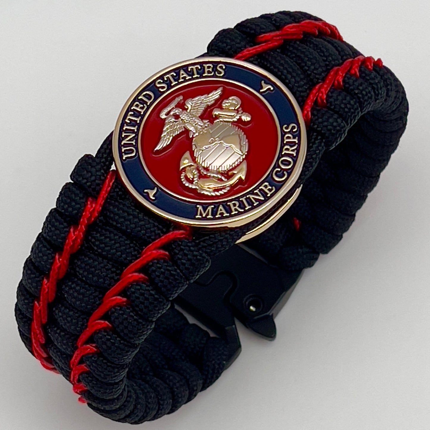 Thick and comfortable braided United States Marine Corps bracelet featuring a 24K gold and silver plated USMC officer Eagle Globe and Anchor medallion, a black Cobra style tactical buckle and woven with black 550 paracord and Imperial Red micro cord.