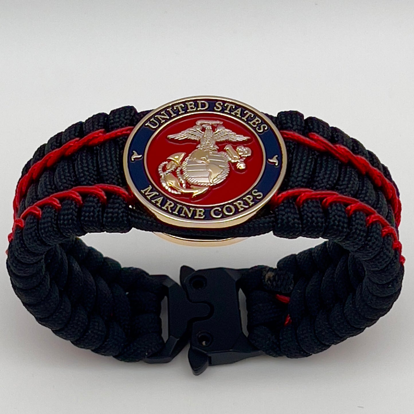 Thick and comfortable braided United States Marine Corps bracelet featuring a 24K gold and silver plated USMC officer Eagle Globe and Anchor medallion, a black Cobra style tactical buckle and woven with black 550 paracord and Imperial Red micro cord.